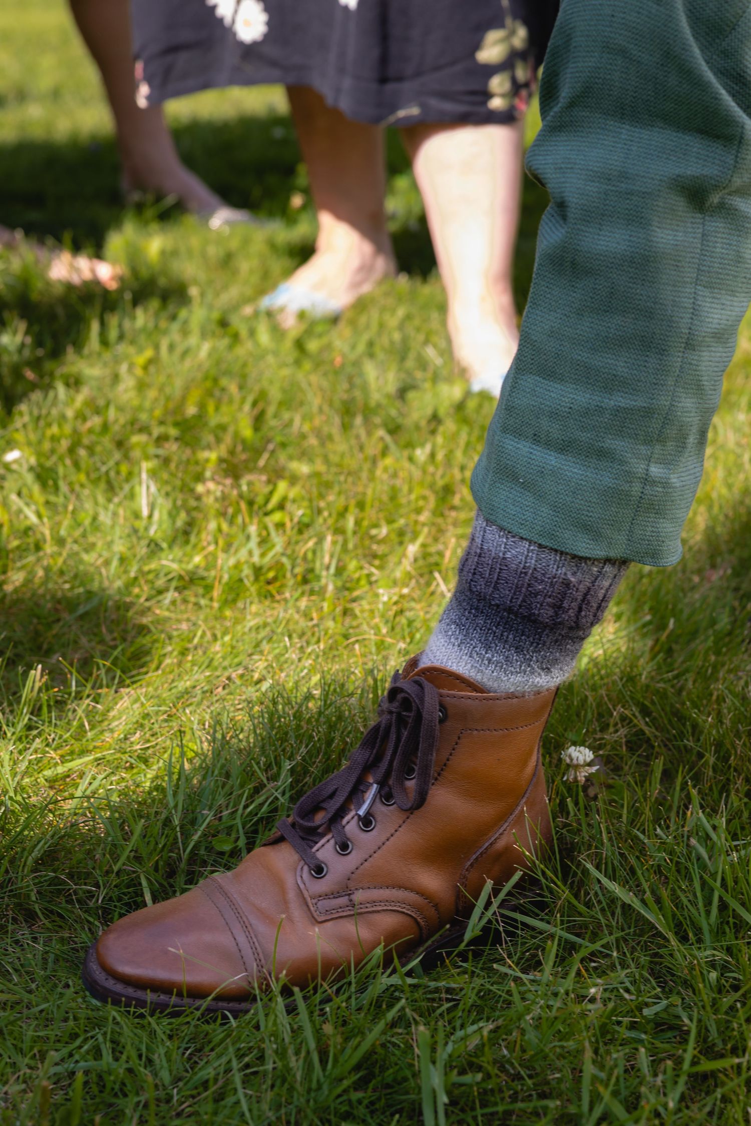 Brown leather lace-up boots with dark socks shown on grass in a sequence of close-up detail shots.