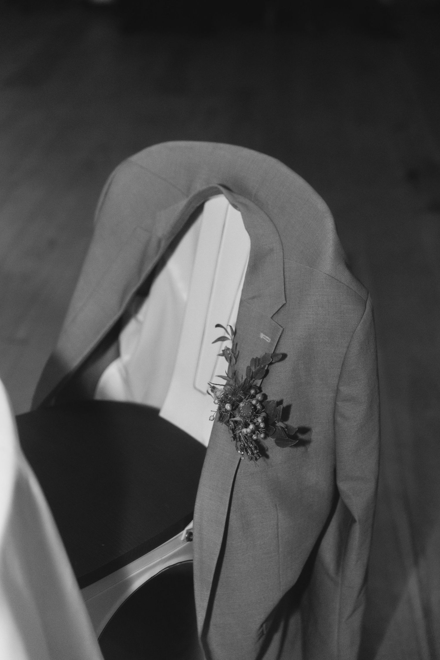 A close-up detail shot of a boutonniere on a grey suit jacket.