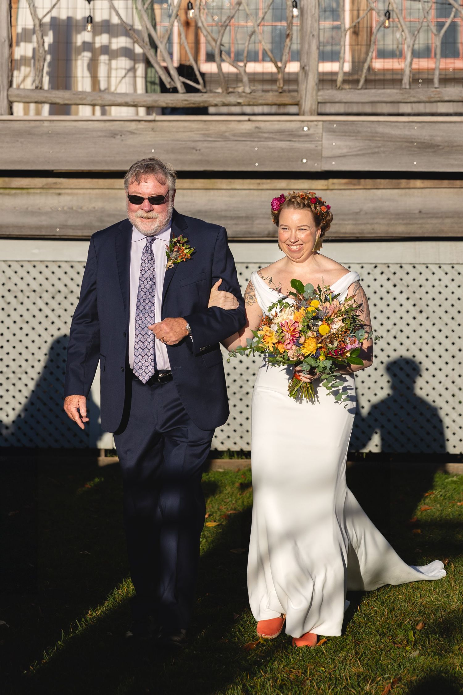 Wedding couple walking together outdoors, with bride holding colorful autumn bouquet.
