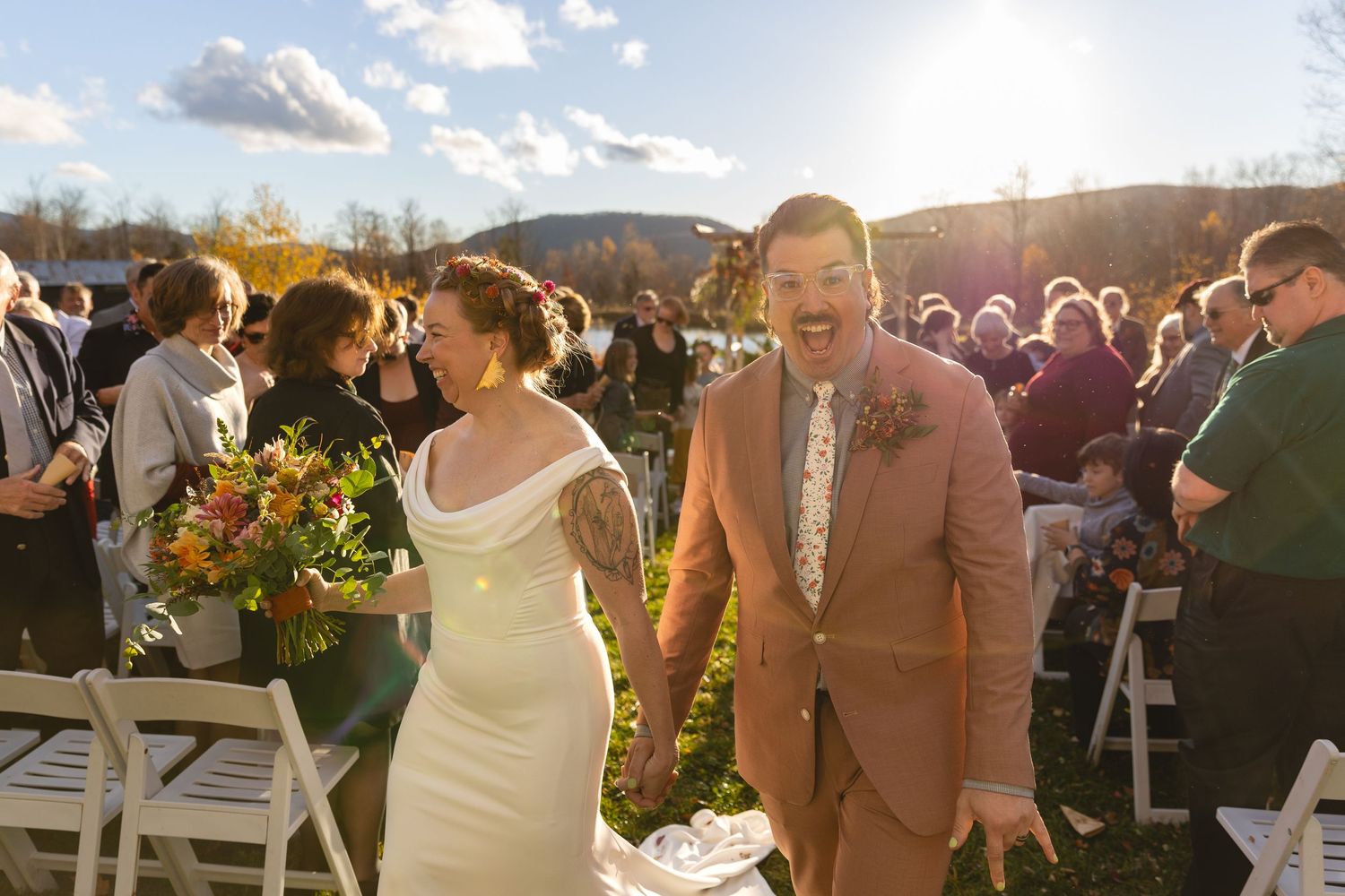 Wedding couple walks down the aisle together during an outdoor autumn ceremony with mountains in background.
