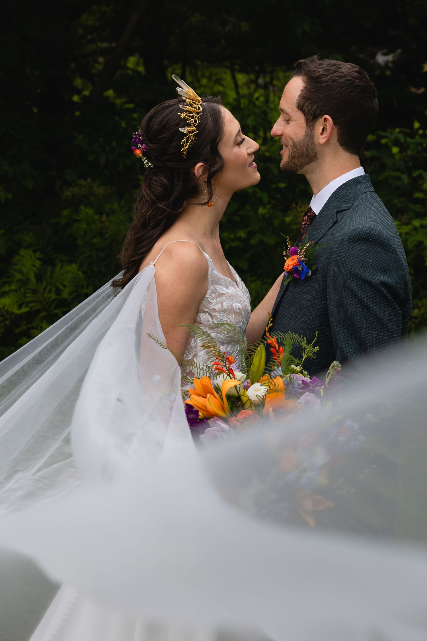 Intimate wedding moment captured against lush green forest backdrop.