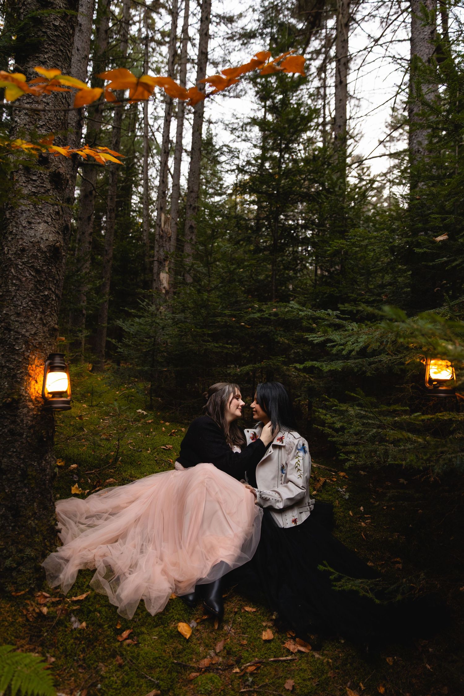 A couple shares a romantic kiss surrounded by glowing lanterns in an enchanting autumn forest.