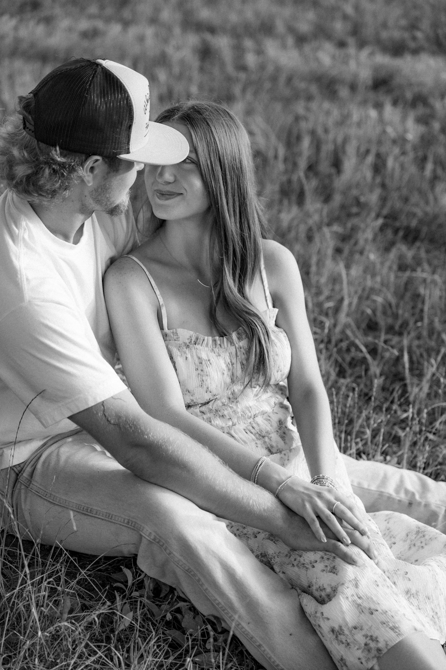 Romantic couple photos in a natural grass field setting with large trees at sunset.