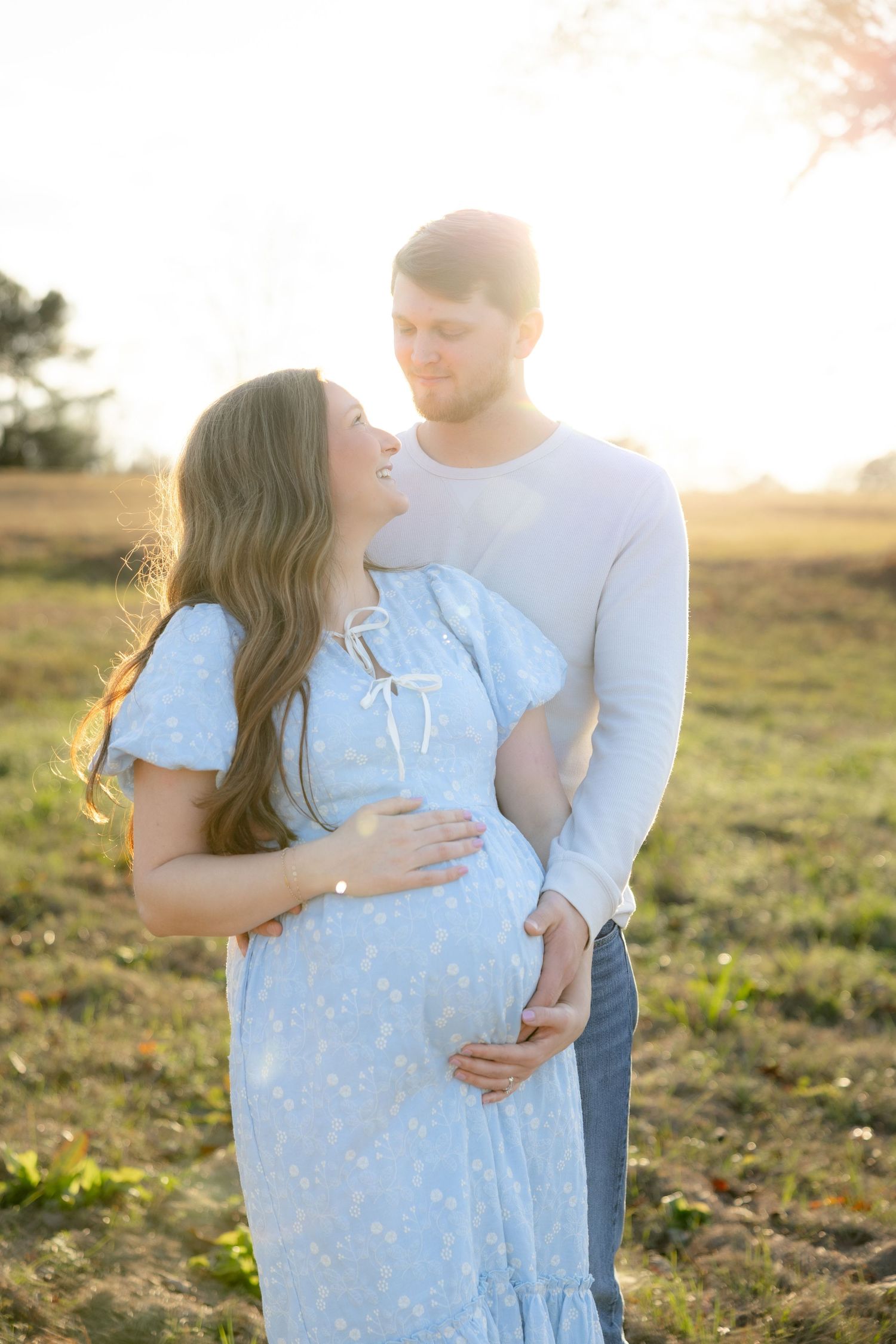 Expecting couple holding each other in a field at sunset in Dothan, Alabama