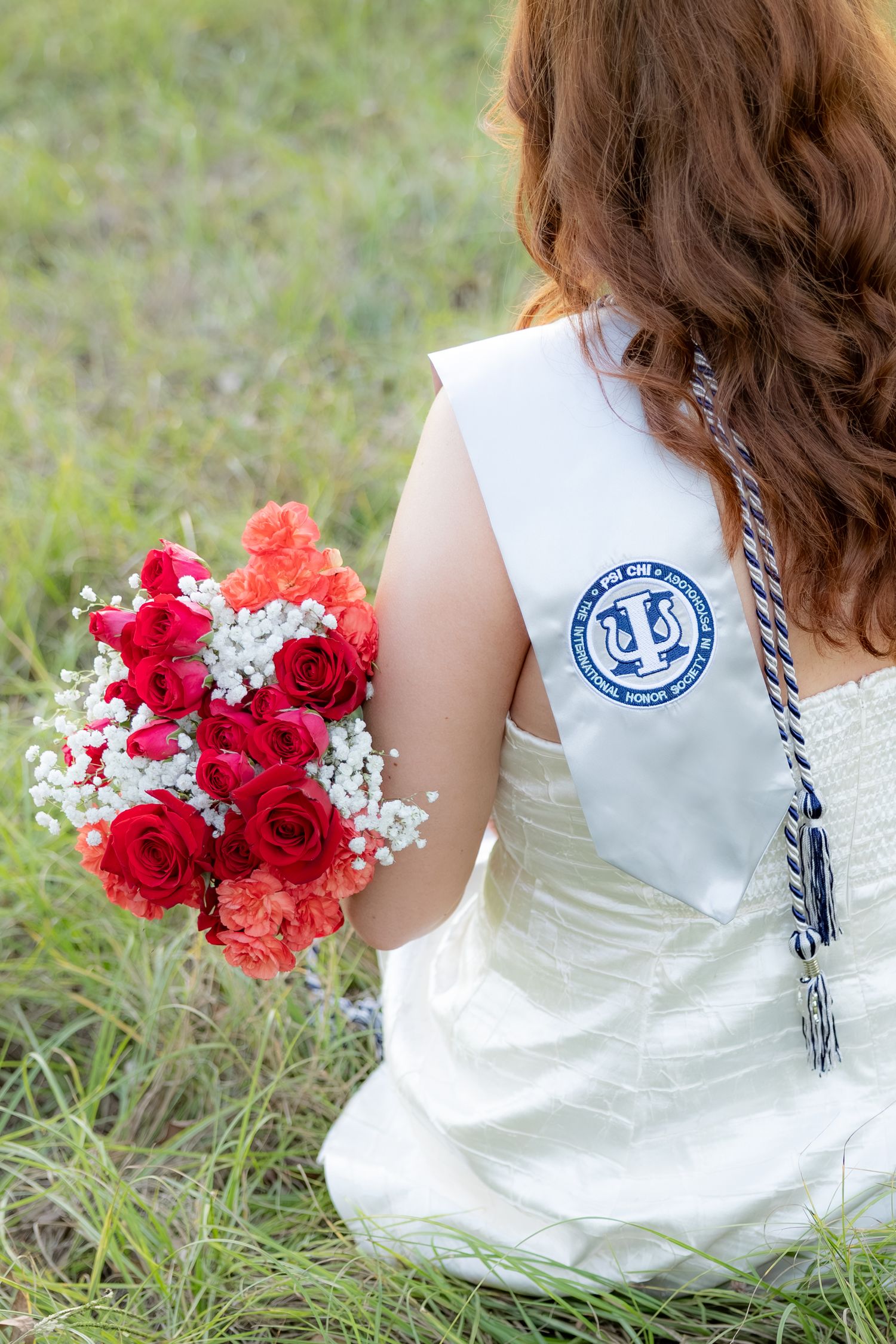 Senior pictures sitting in a field at sunset at Troy University Dothan Campus