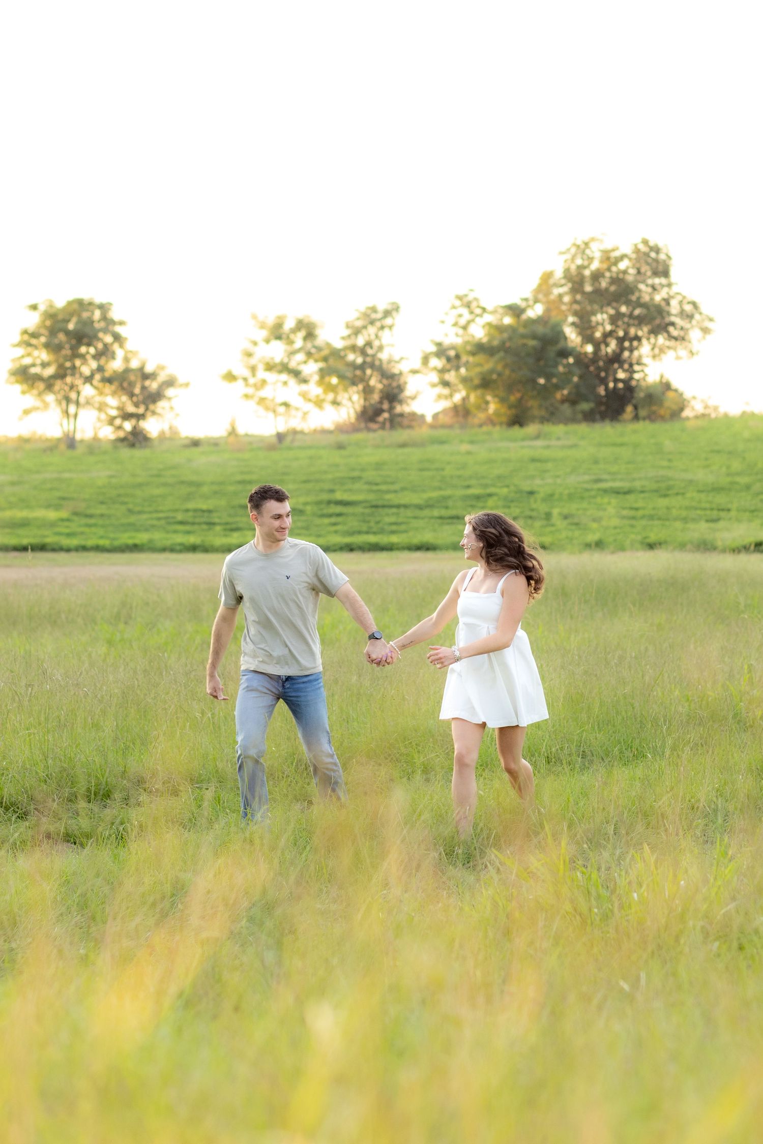 Couple running through a grass field in Dothan, Alabama