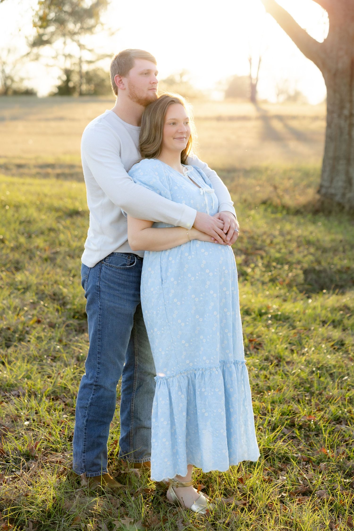Expecting couple holding each other in a field at sunset in Dothan, Alabama