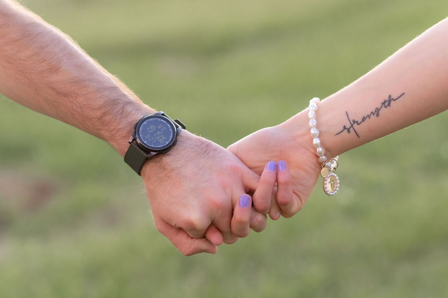 Couple holding hands detail in a grass field in Dothan, Alabama