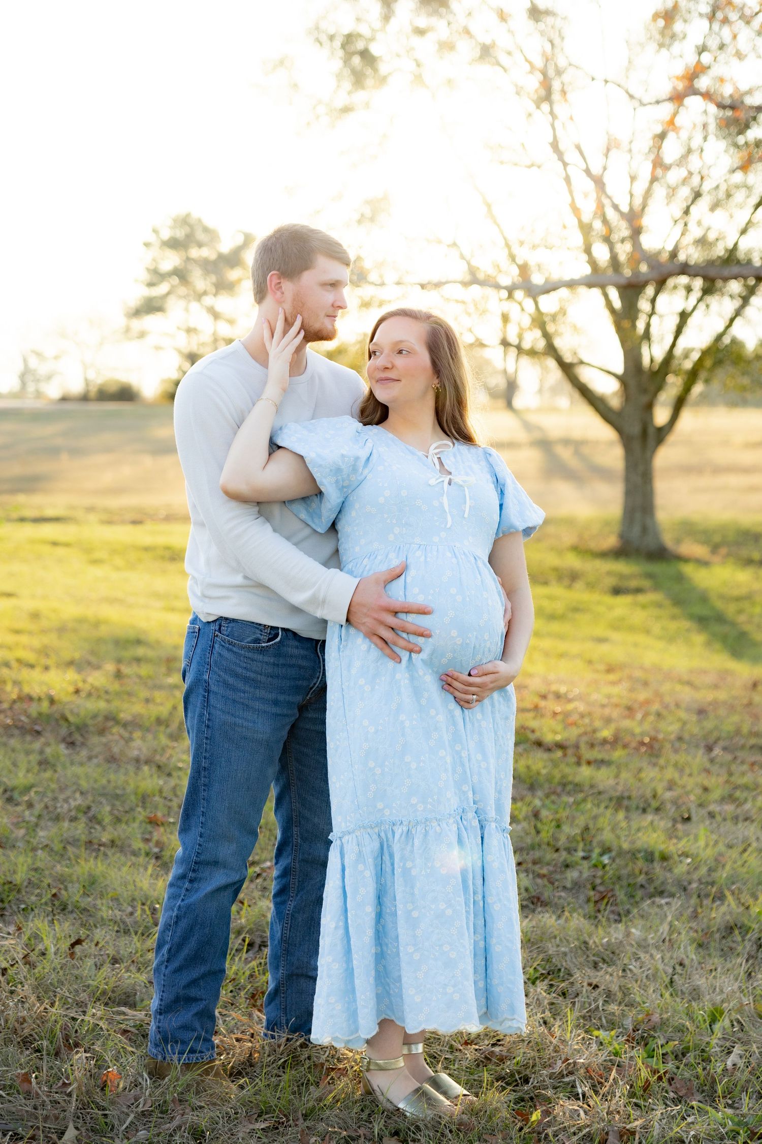 Expecting couple holding each other in a field at sunset in Dothan, Alabama