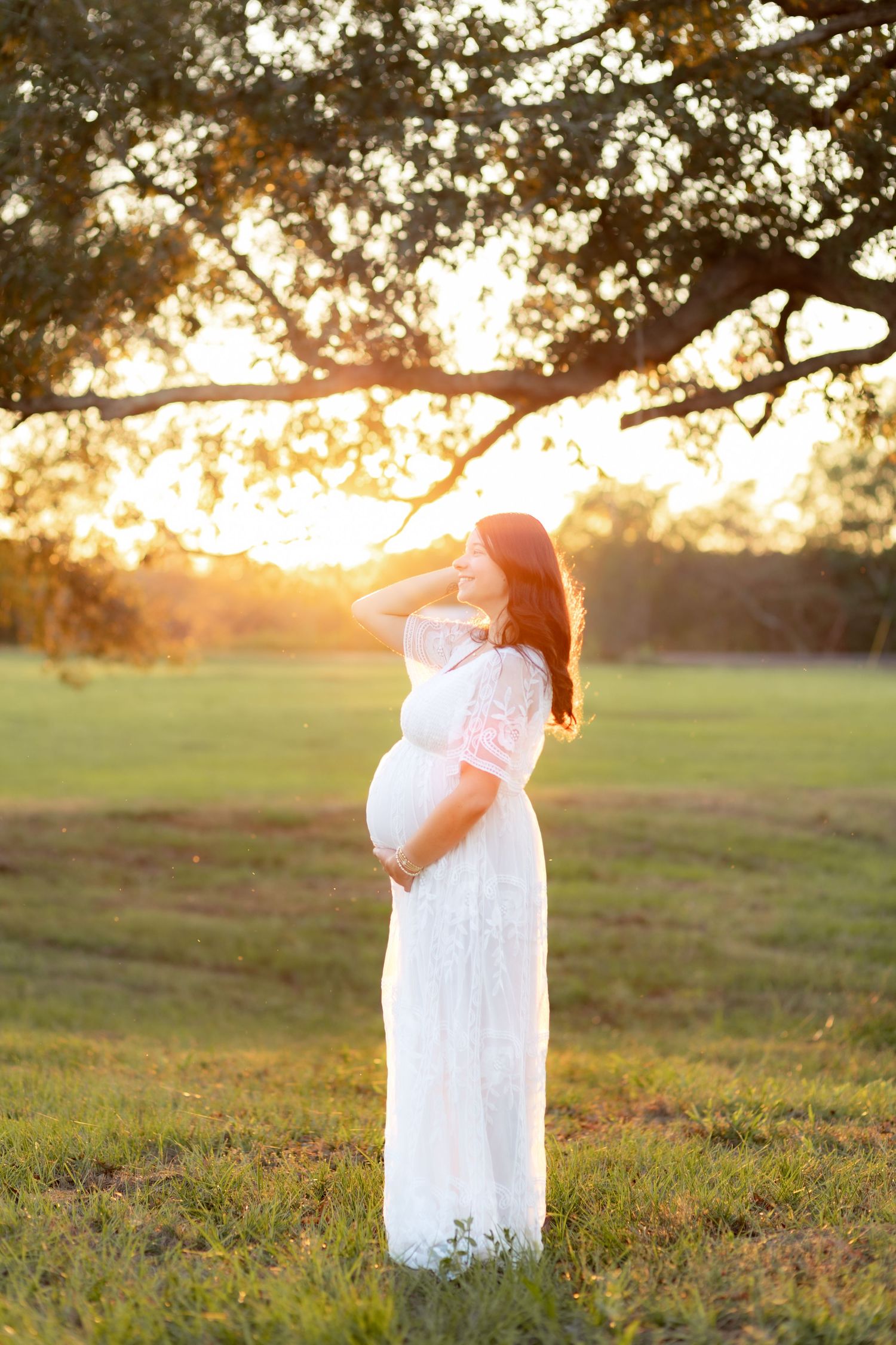 Expecting mother standing in a grass field at sunset in Dothan, Alabama