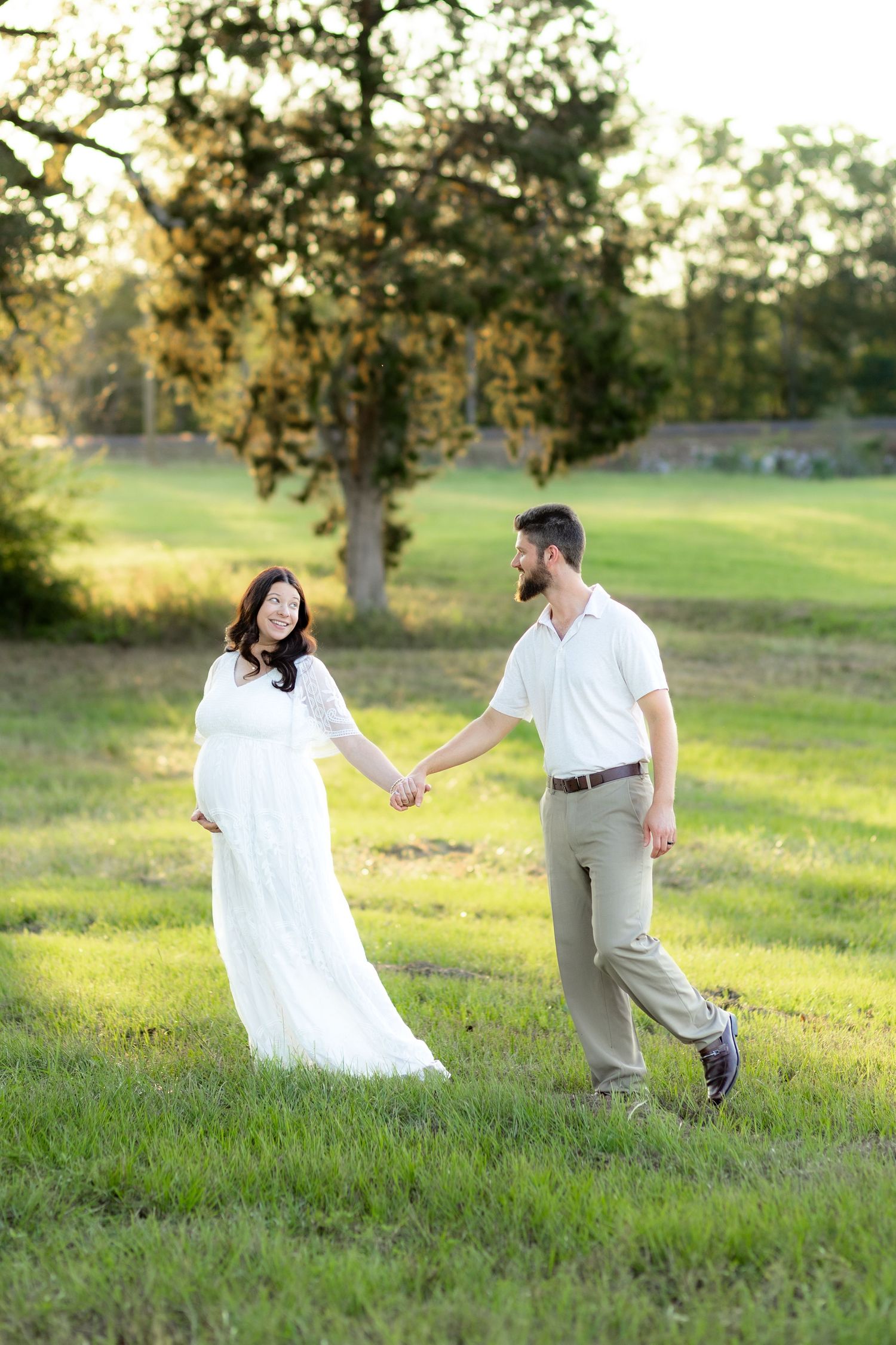 Expecting couple walking in a grass field at sunset in Dothan, Alabama