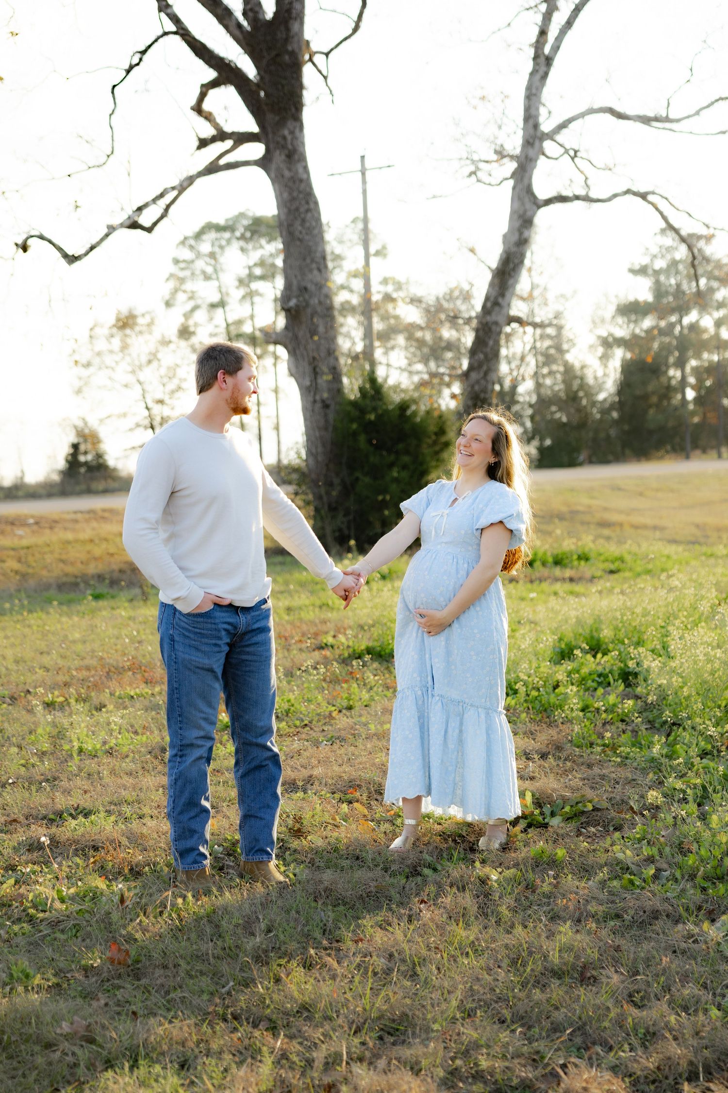 Expecting couple holding each other in a field at sunset in Dothan, Alabama