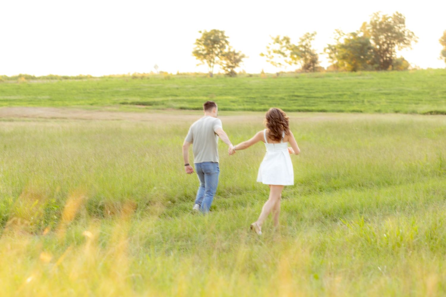 Couple running through a grass field at sunset in Dothan, Alabama