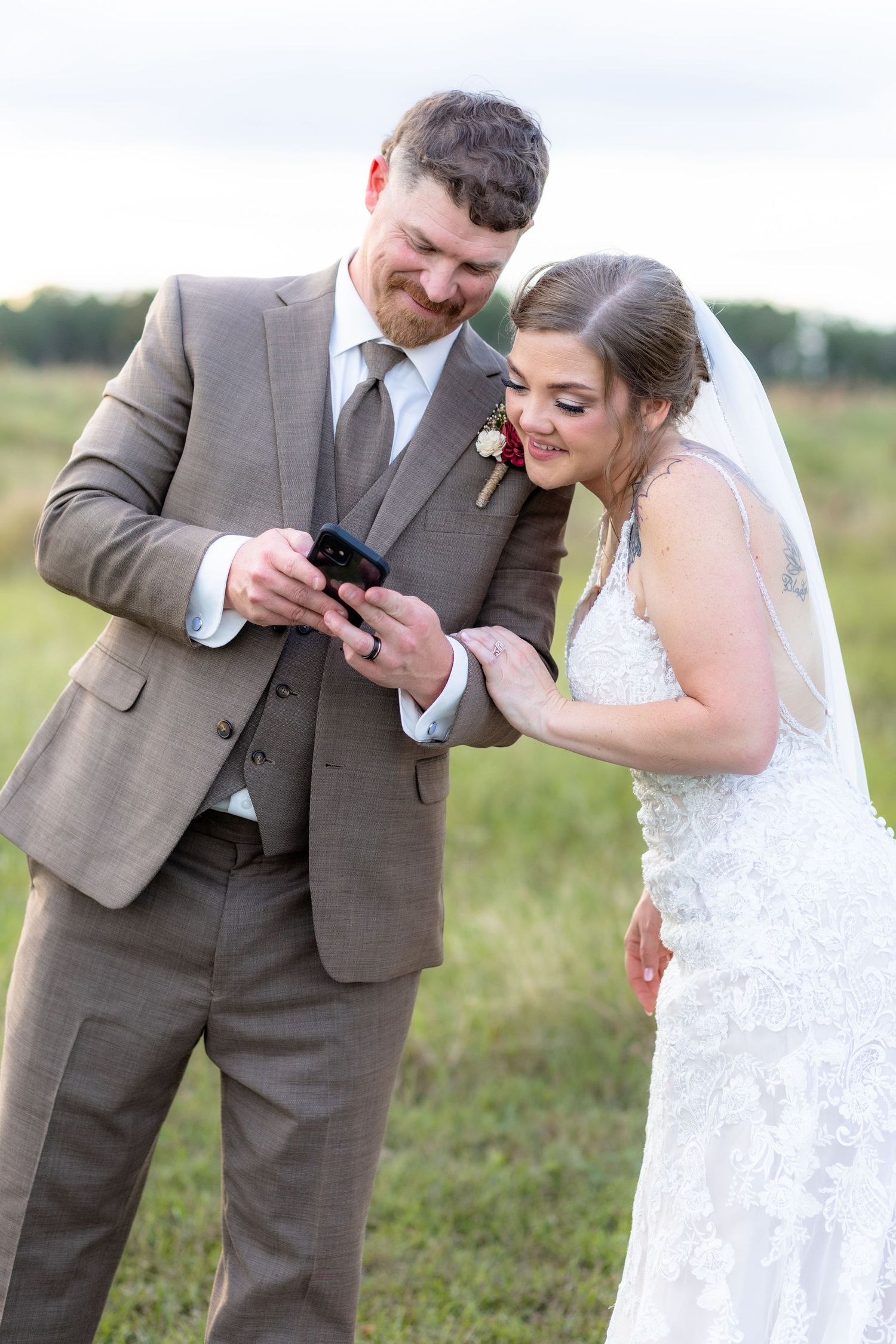 Bride and groom share a moment looking at a phone at Hilltop Acres Wicksburg, Alabama