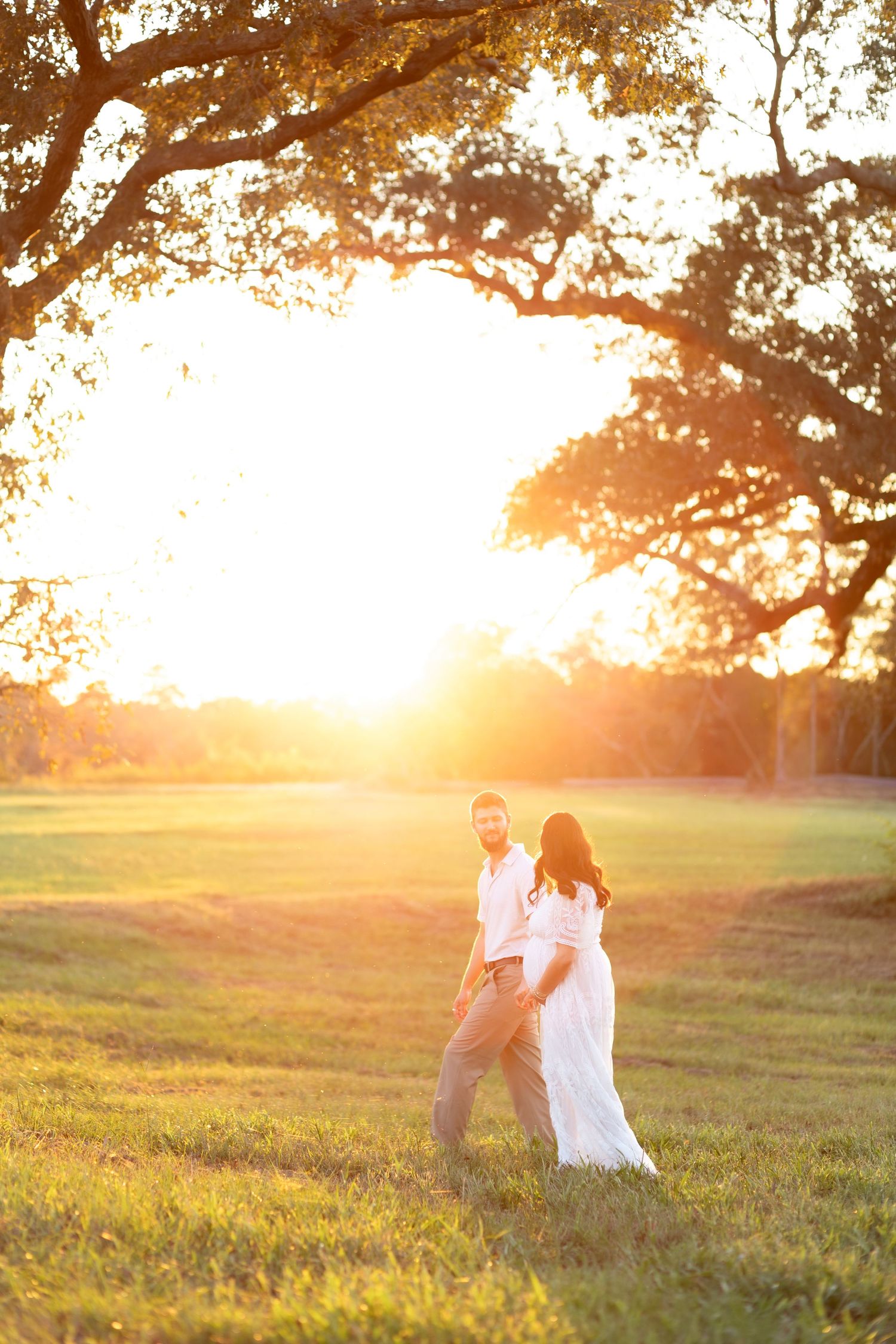 Expecting couple walking in a grass field at sunset in Dothan, Alabama