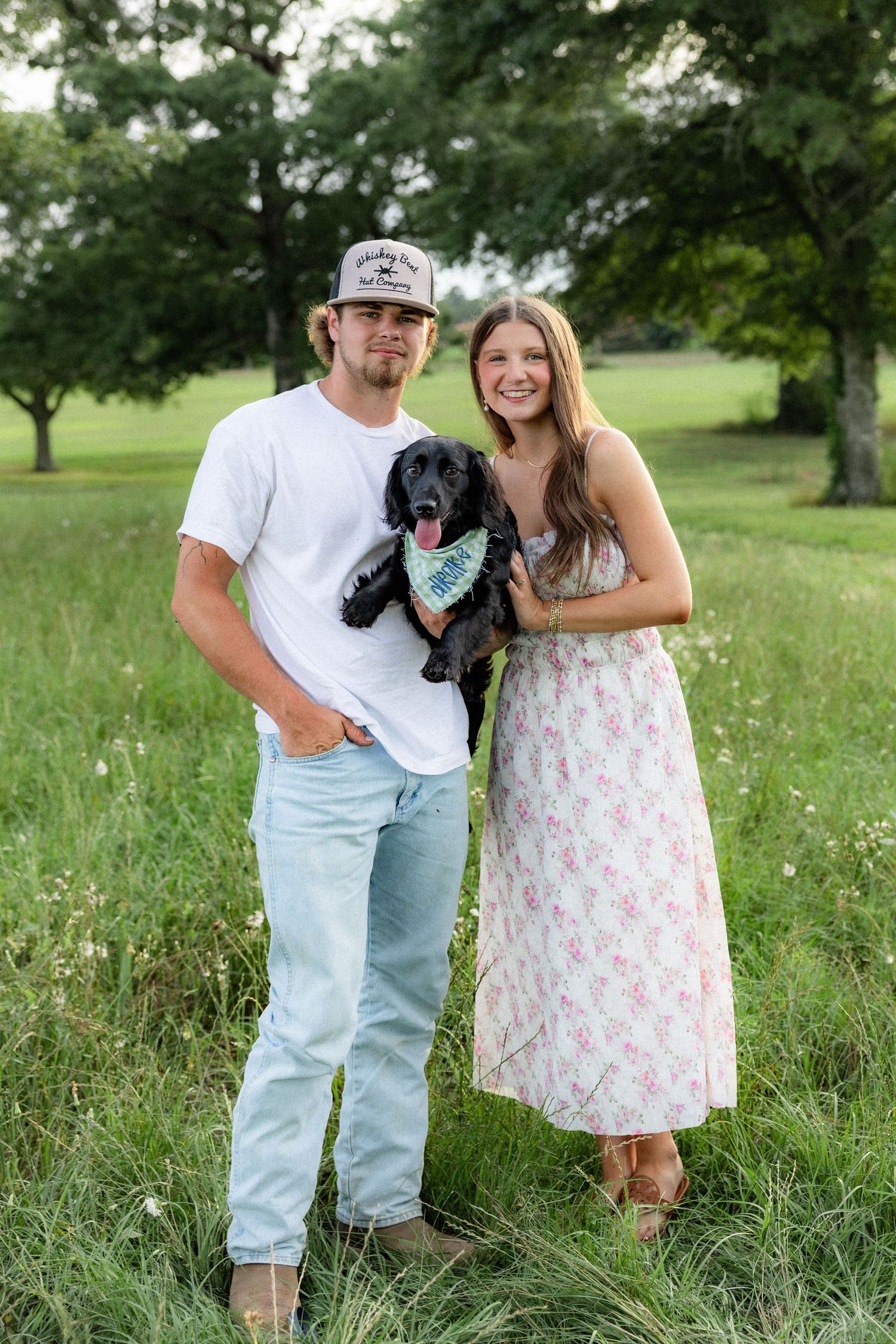 Romantic couple photos in a natural grass field setting with large trees at sunset.
