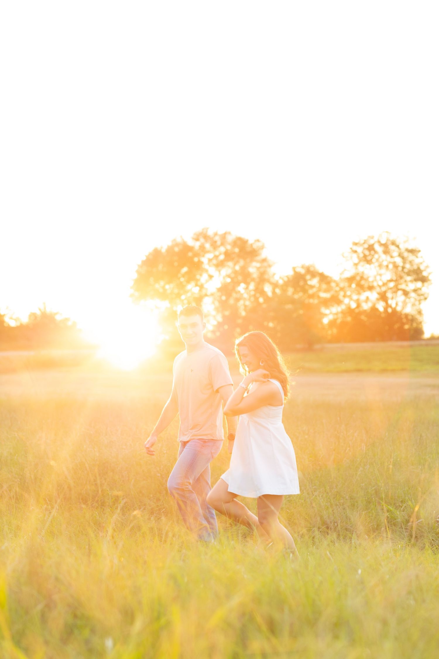 Couple running through a grass field at sunset in Dothan, Alabama