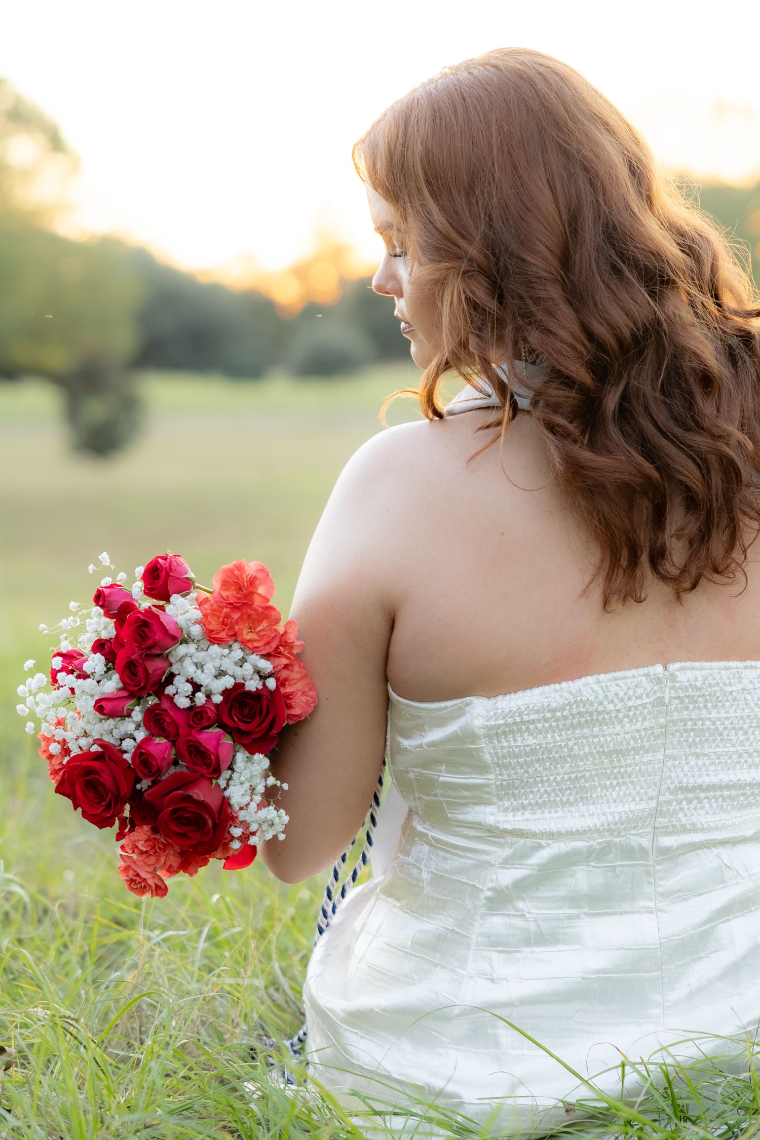 Senior pictures sitting in a field at sunset at Troy University Dothan Campus