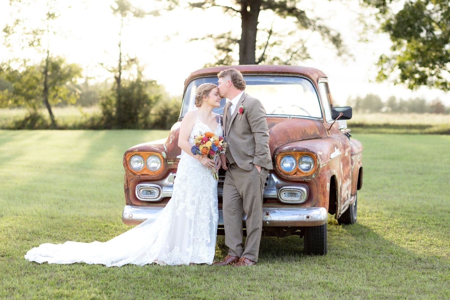 Bride and groom pose in front of a rustic chevy at sunset at Hilltop Acres Wicksburg, Alabama