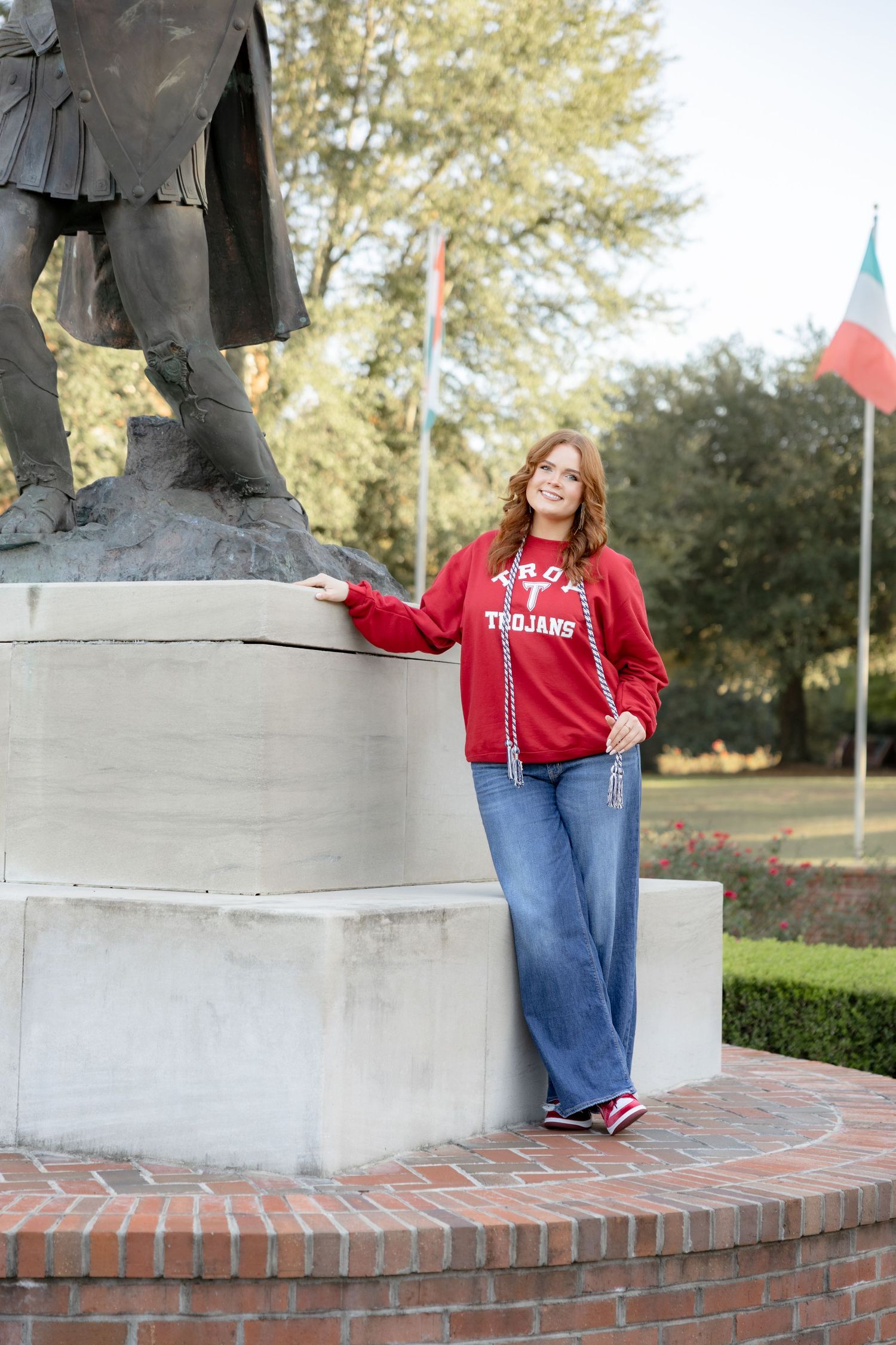 Troy graduate standing beside Troy University's Trojan at Troy University Dothan Campus