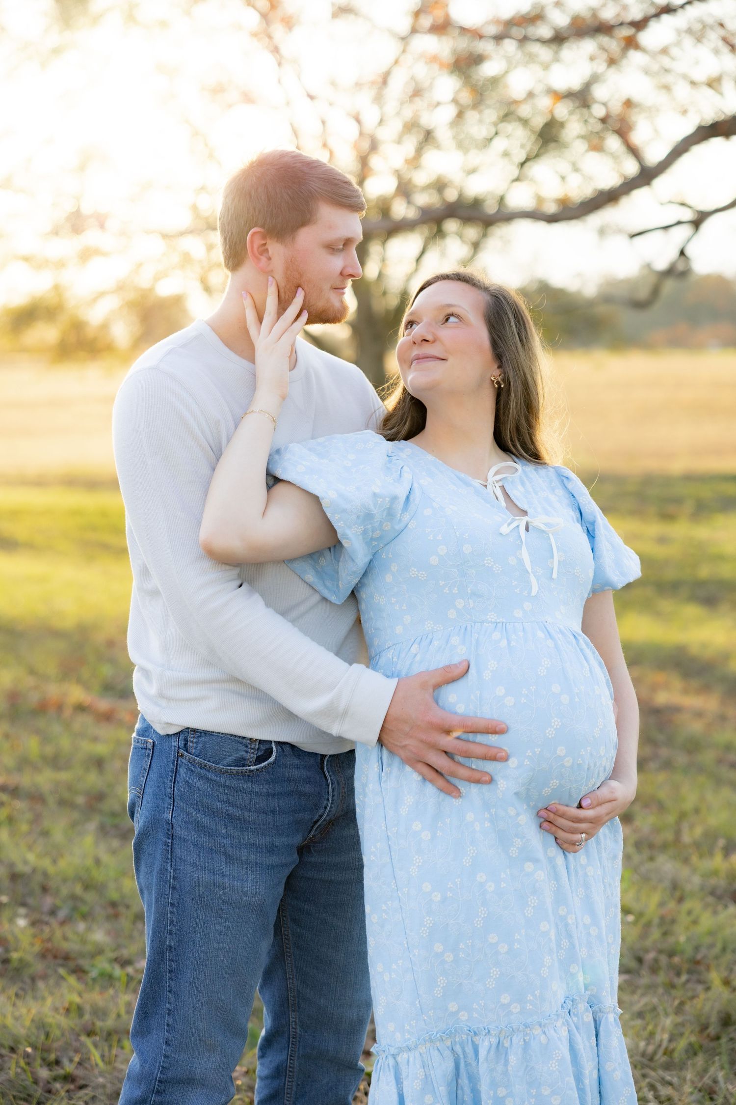 Expecting couple holding each other in a field at sunset in Dothan, Alabama