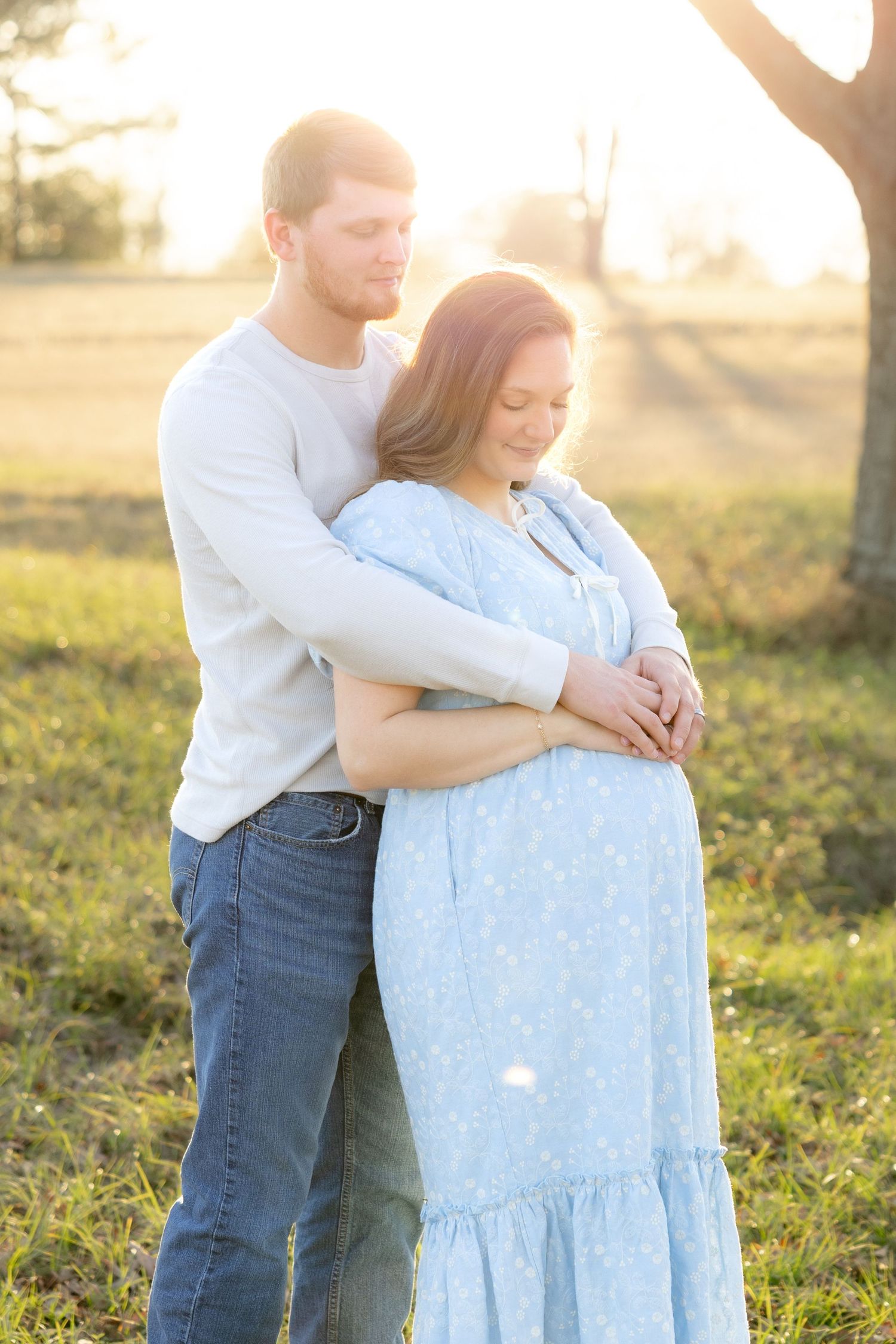 Expecting couple holding each other in a field at sunset in Dothan, Alabama