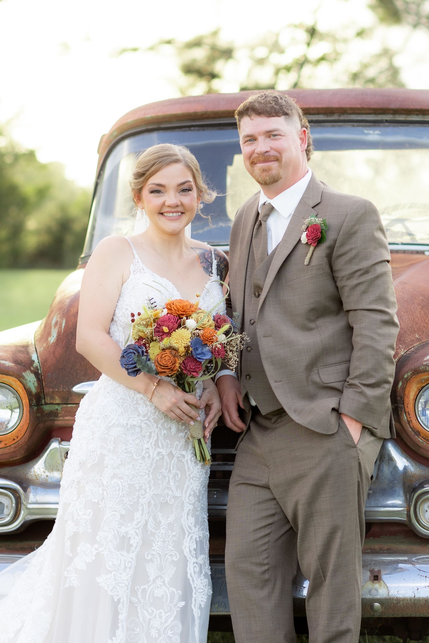 Bride and groom pose in front of a rustic chevy at sunset at Hilltop Acres Wicksburg, Alabama