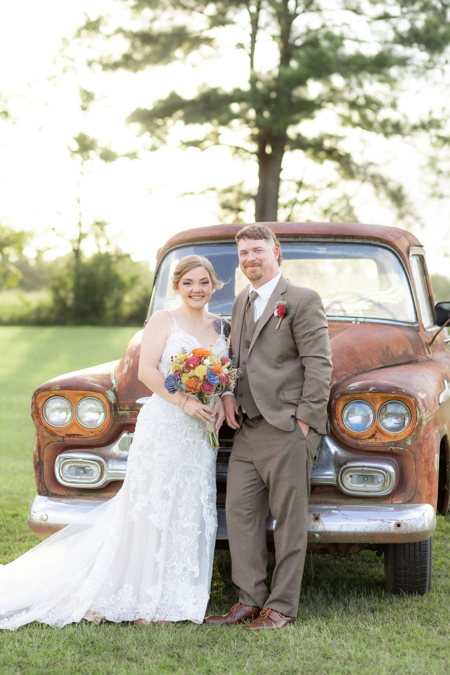 Bride and groom pose in front of a rustic chevy at sunset at Hilltop Acres Wicksburg, Alabama
