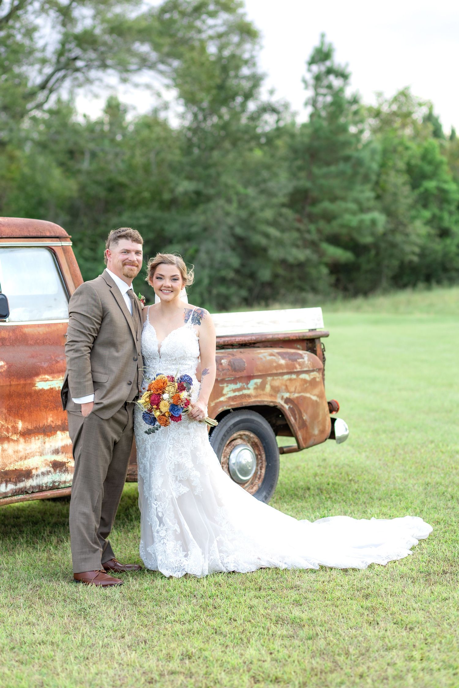 Bride and groom pose in front of a rustic chevy at sunset at Hilltop Acres Wicksburg, Alabama