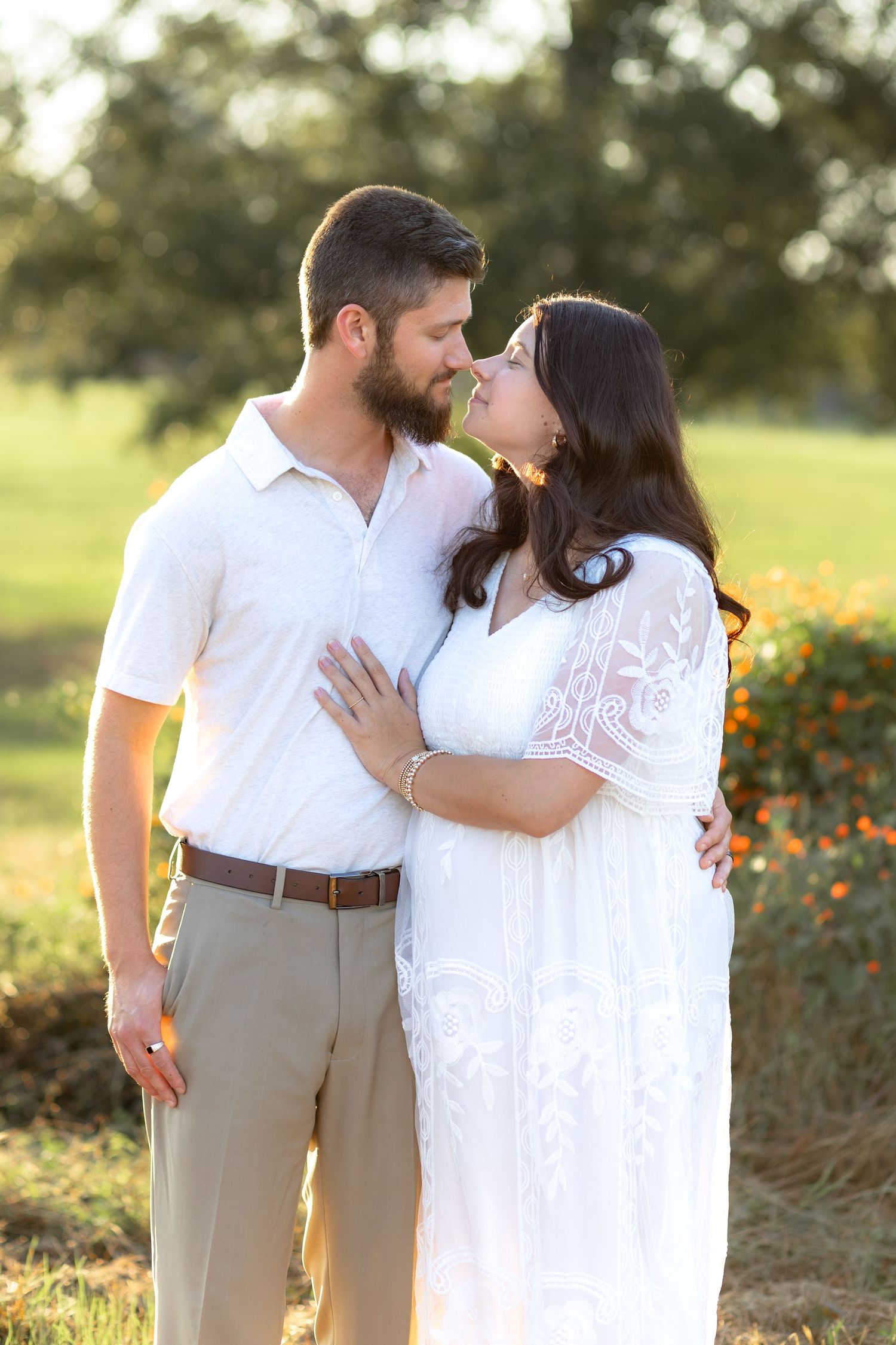 Expecting couple holding each other in a grass field at sunset in Dothan, Alabama