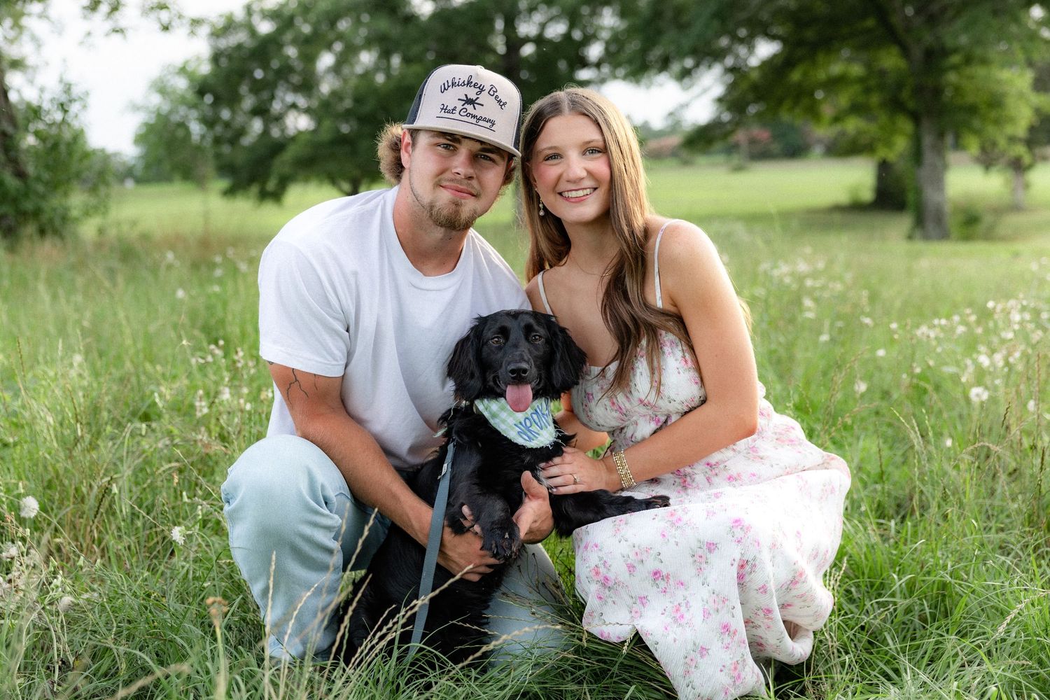 Romantic couple photos in a natural grass field setting with large trees at sunset.