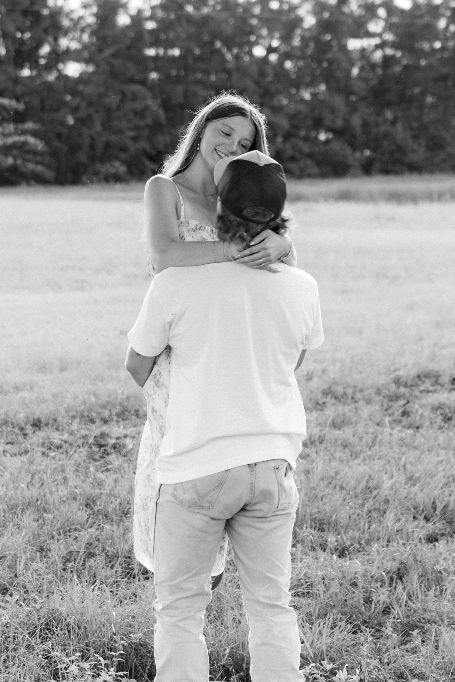 Romantic couple photos in a natural grass field setting with large trees at sunset.