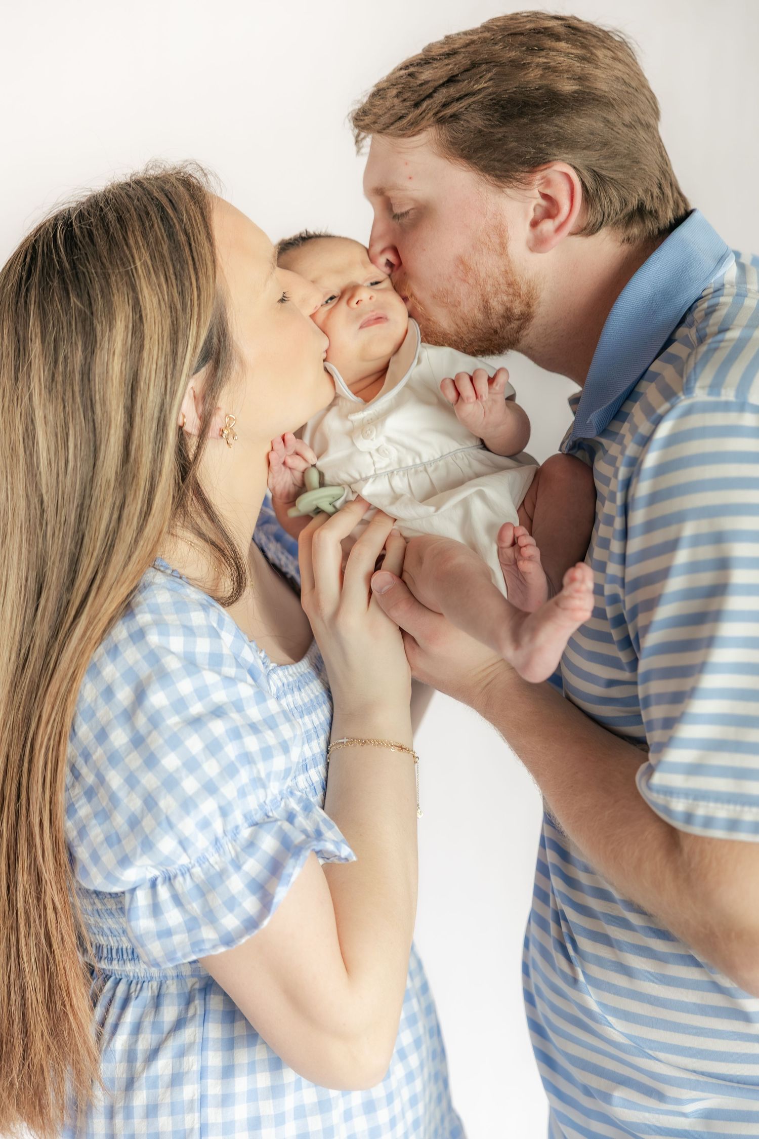 Family kissing their baby in a studio in Dothan, Alabama
