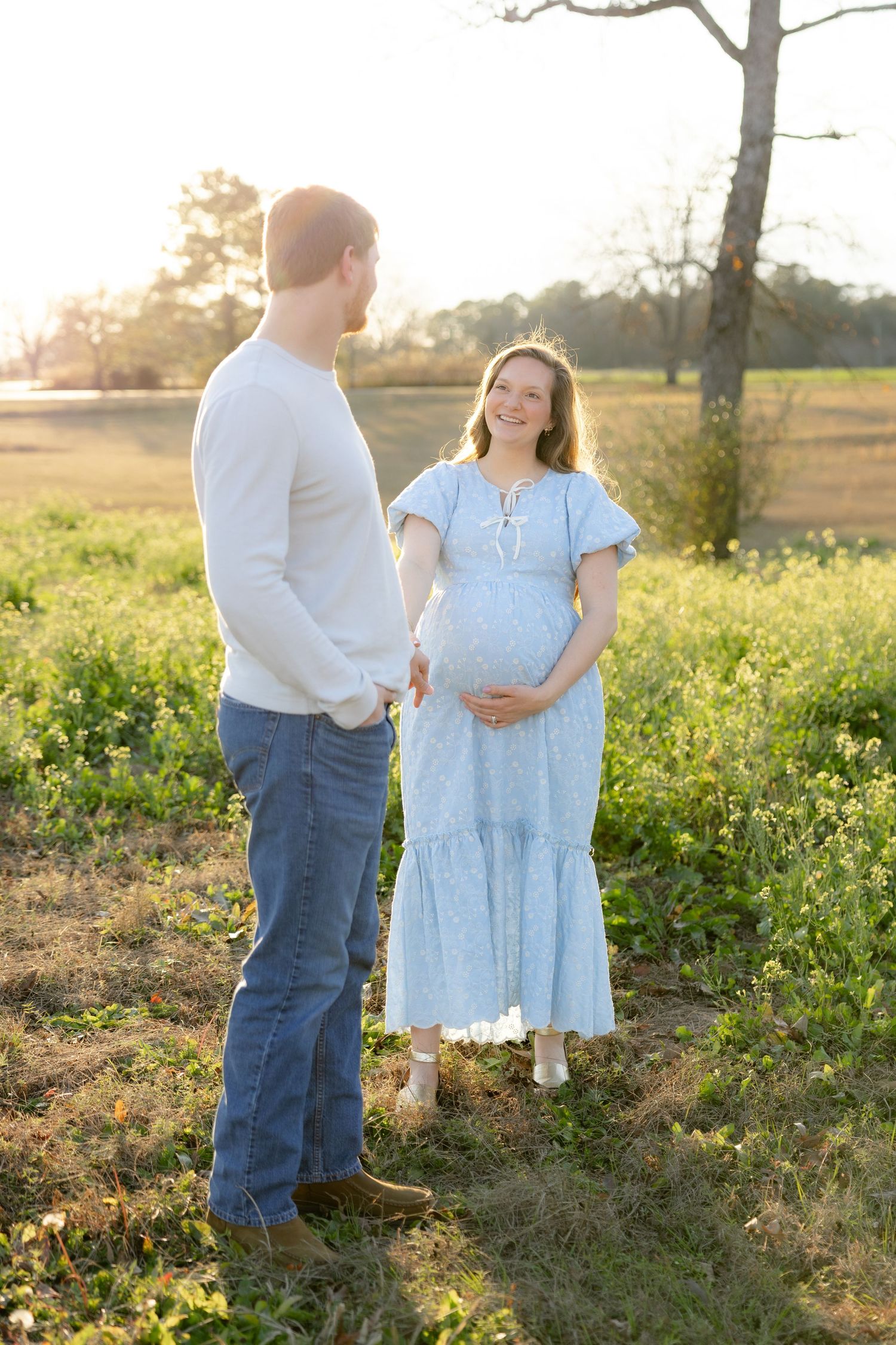 Expecting couple holding each other in a field at sunset in Dothan, Alabama