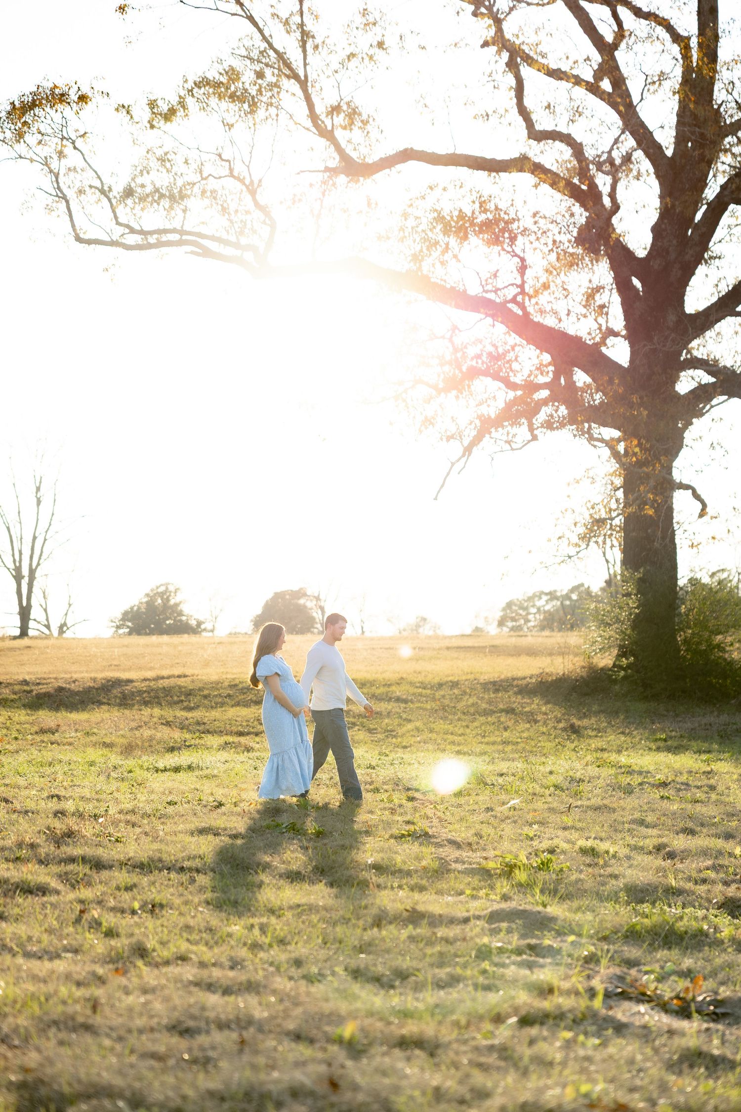 Expecting couple walking in a field at sunset in Dothan, Alabama