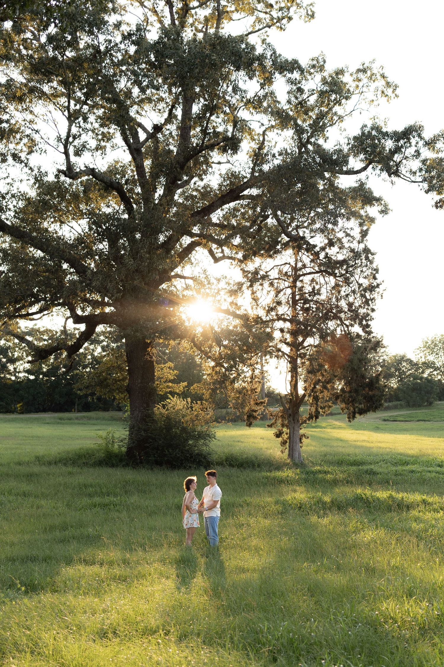 Wide angle shot of a couple in a grass field at sunset in Dothan, Alabama