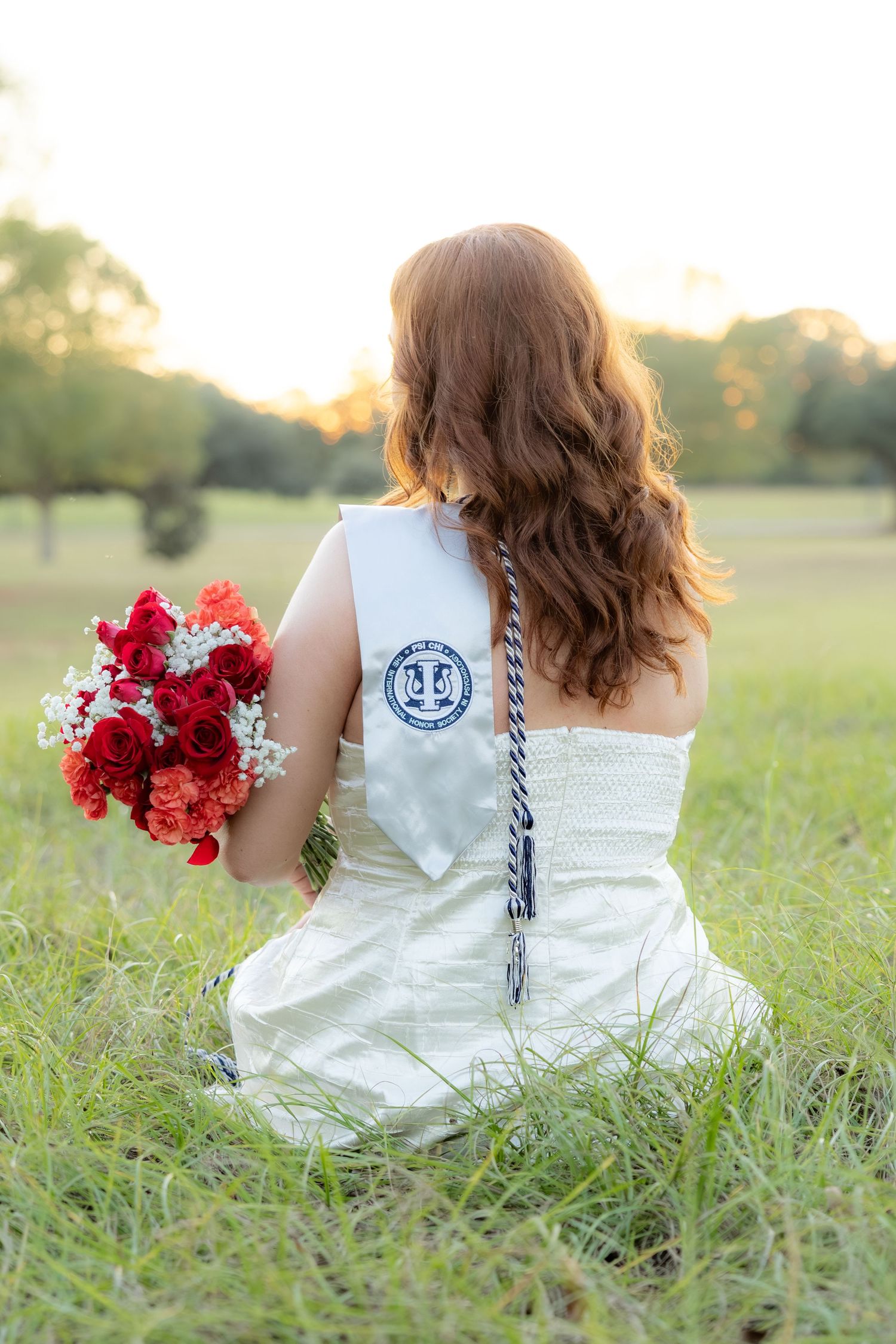 Senior pictures sitting in a field at sunset at Troy University Dothan Campus