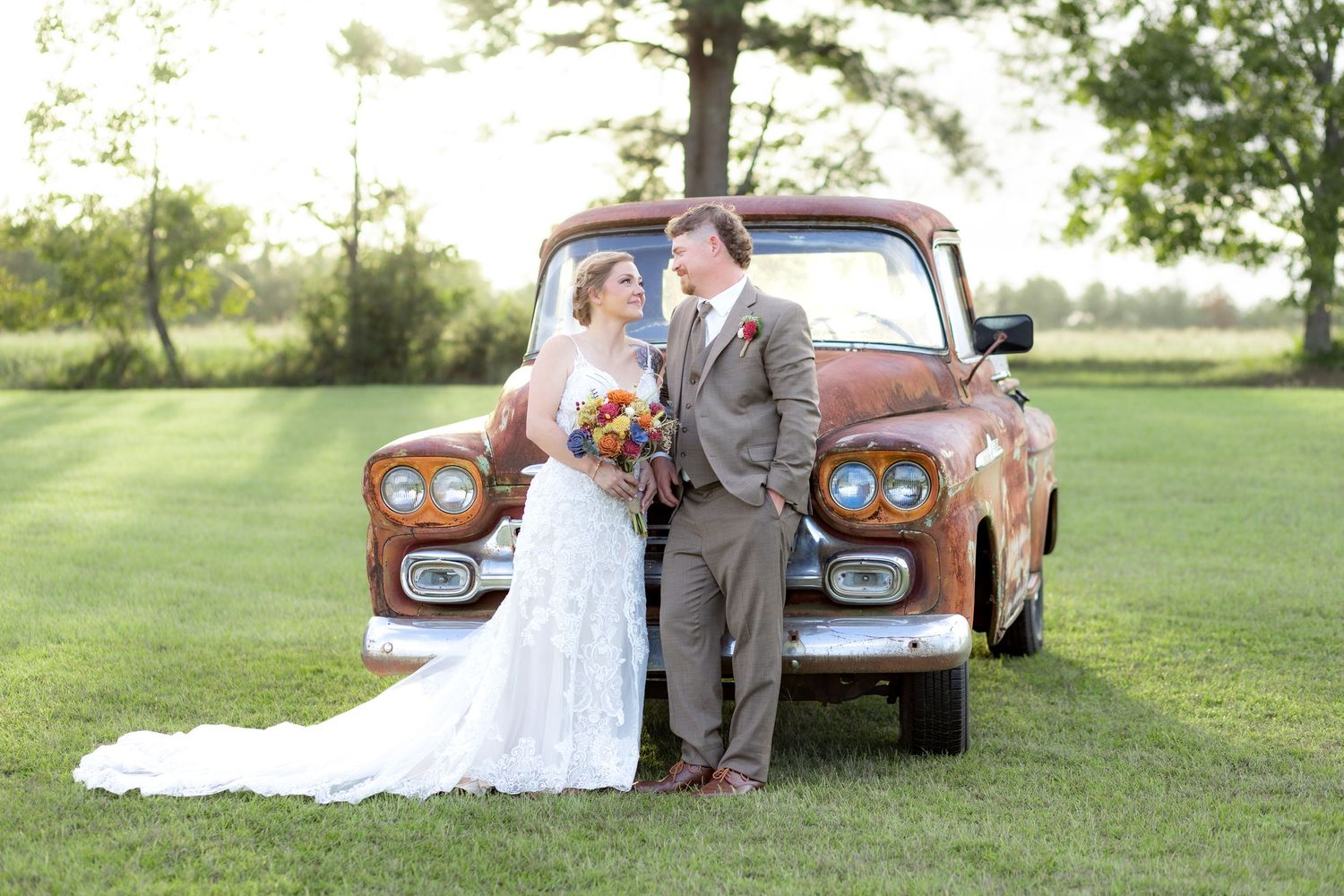 Bride and groom pose in front of a rustic chevy at sunset at Hilltop Acres Wicksburg, Alabama