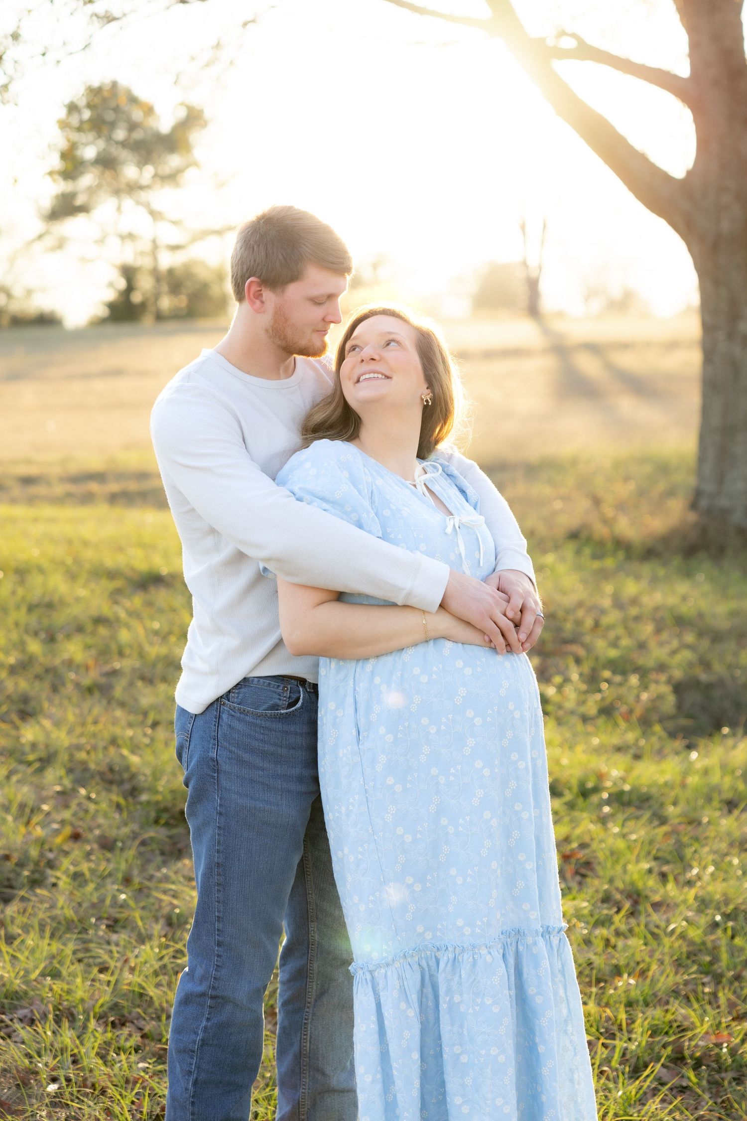 Expecting couple holding each other in a field at sunset in Dothan, Alabama