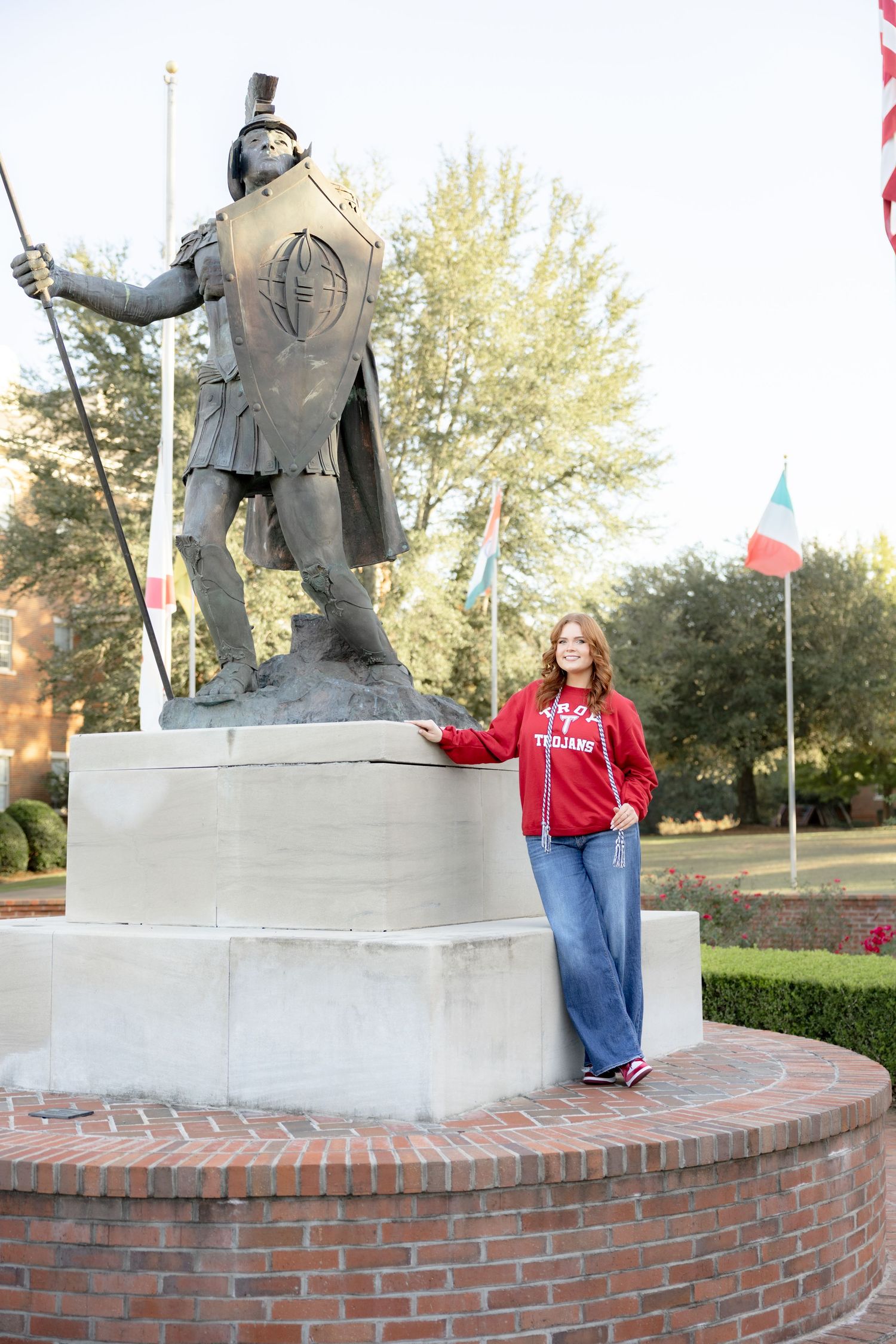 Senior standing beside Troy University's Trojan at Troy University Dothan Campus