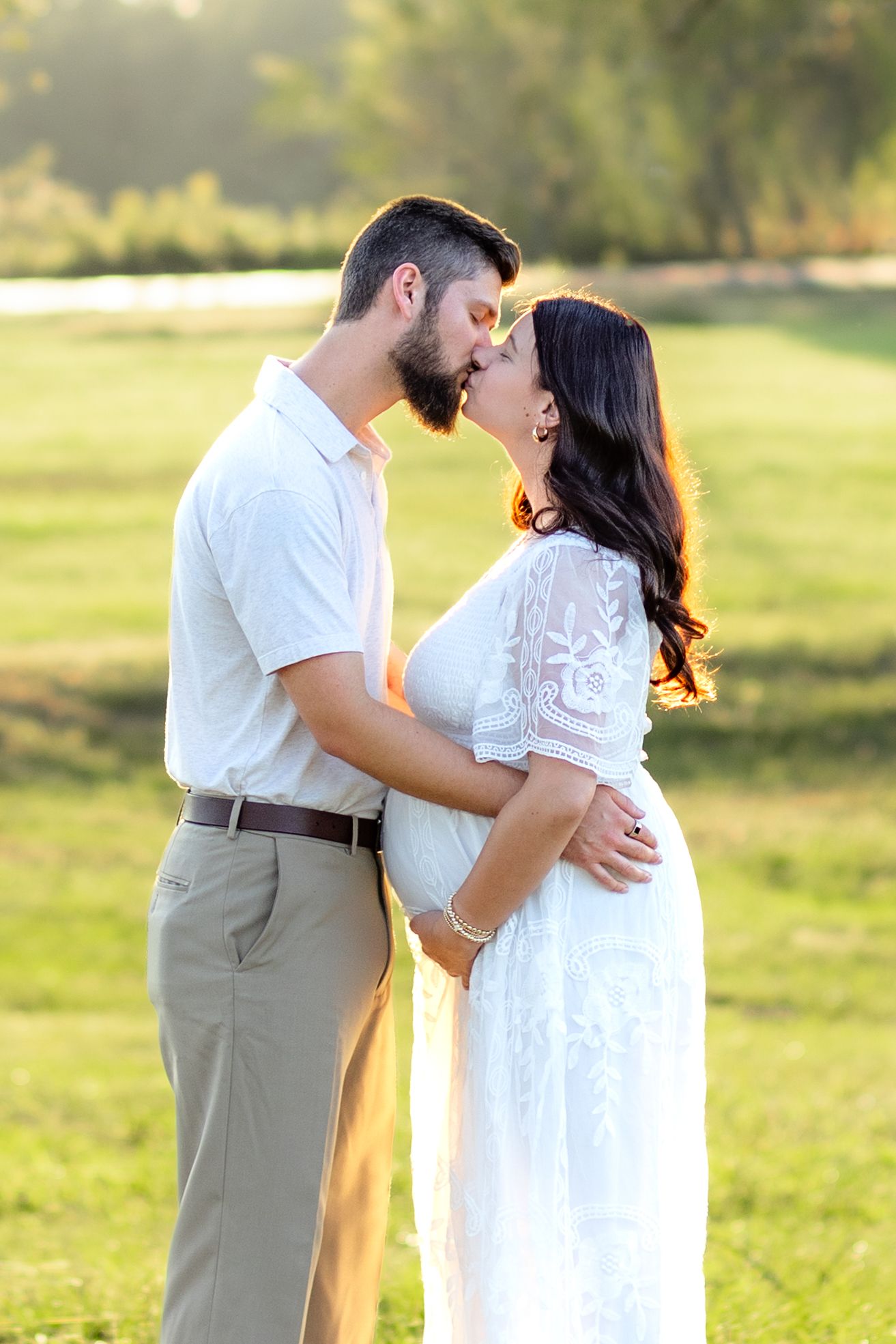 Expecting couple holding each other in a grass field at sunset in Dothan, Alabama