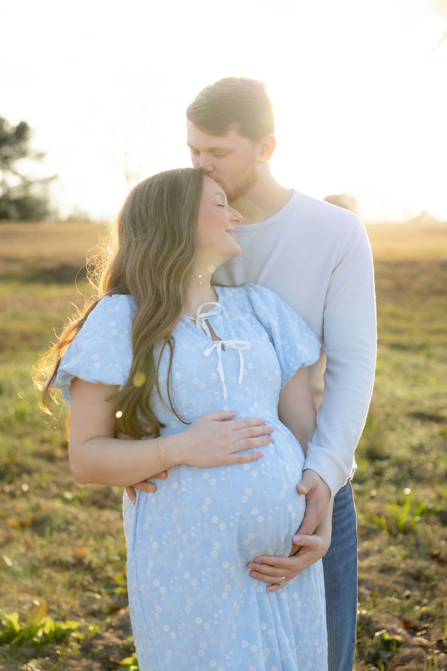 Expecting couple holding each other in a field at sunset in Dothan, Alabama