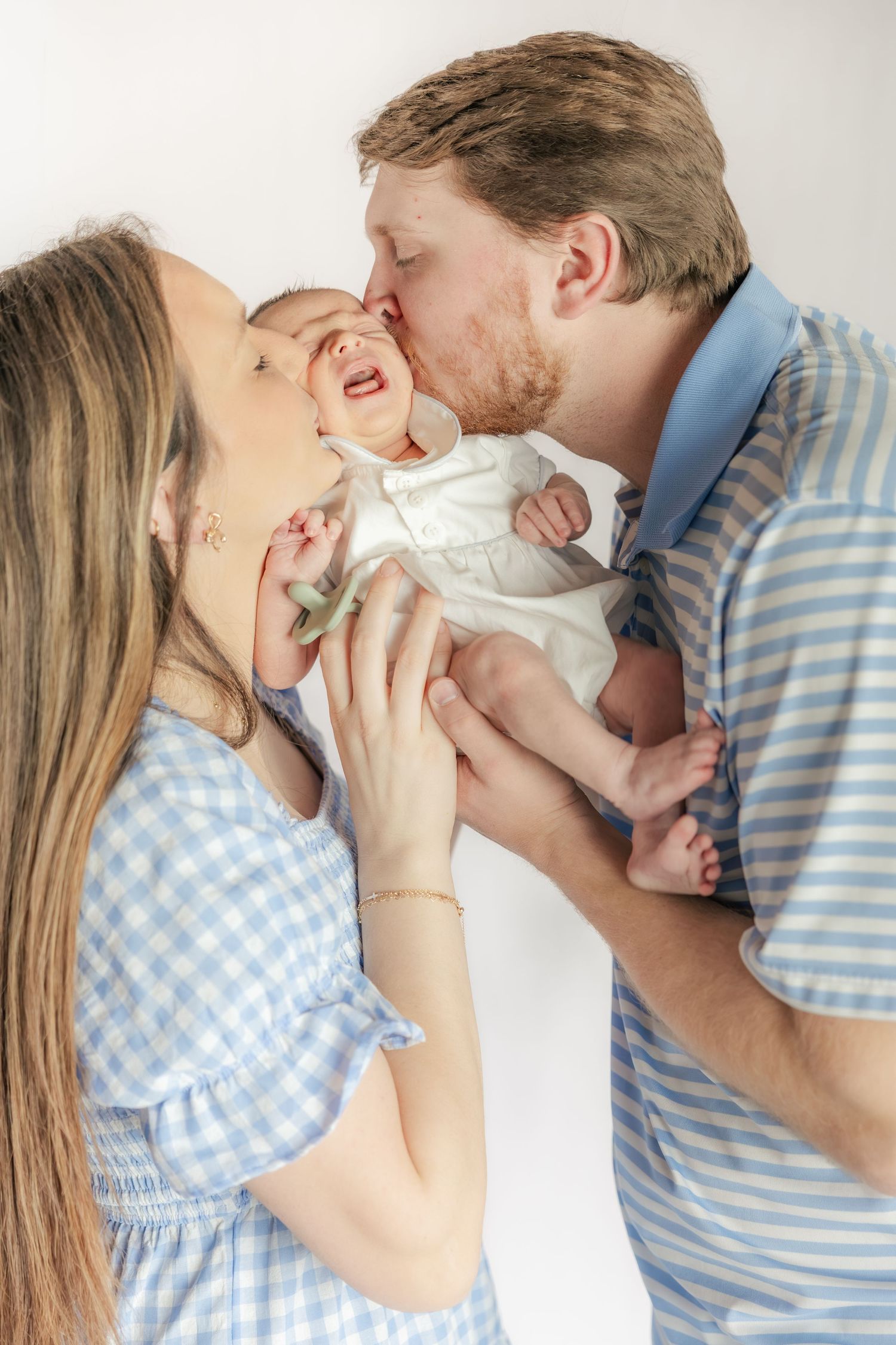 Family kissing their baby in a studio in Dothan, Alabama