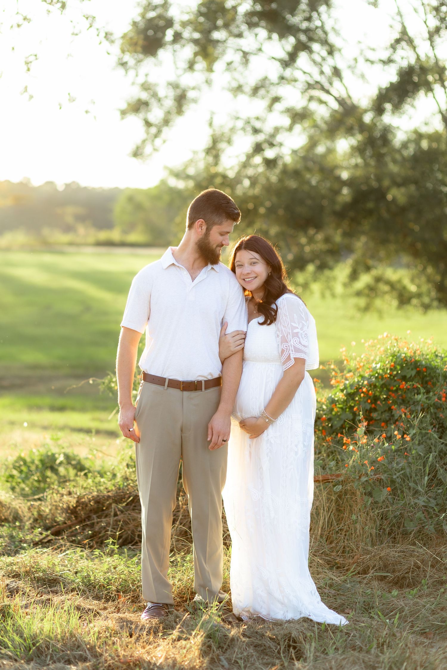 Expecting couple holding each other in a grass field at sunset in Dothan, Alabama