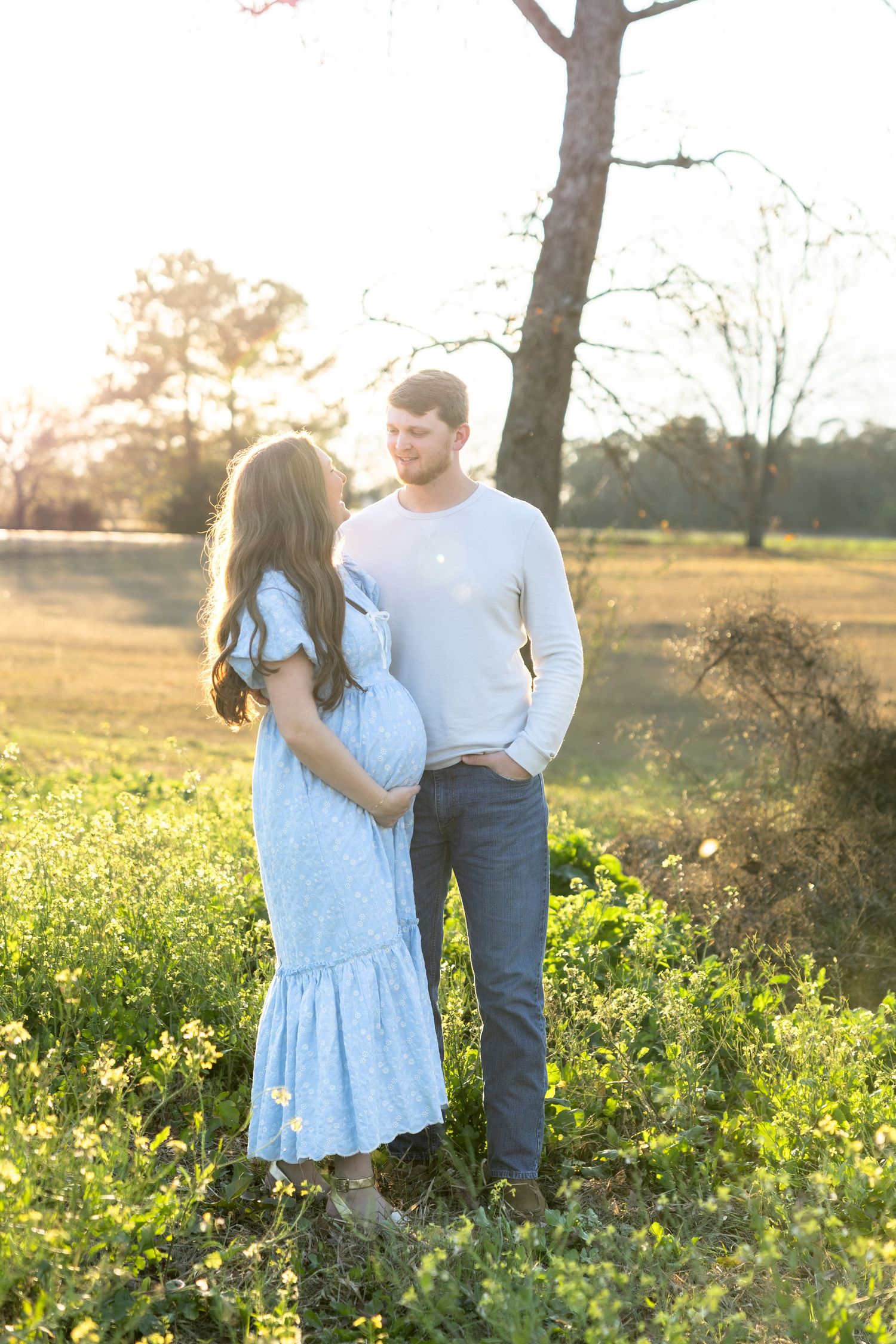 Expecting couple holding each other in a field at sunset in Dothan, Alabama