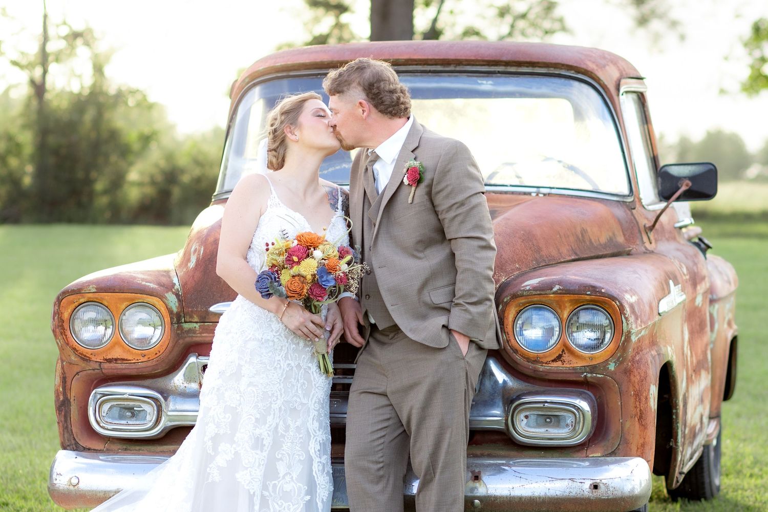 Bride and groom pose in front of a rustic chevy at sunset at Hilltop Acres Wicksburg, Alabama