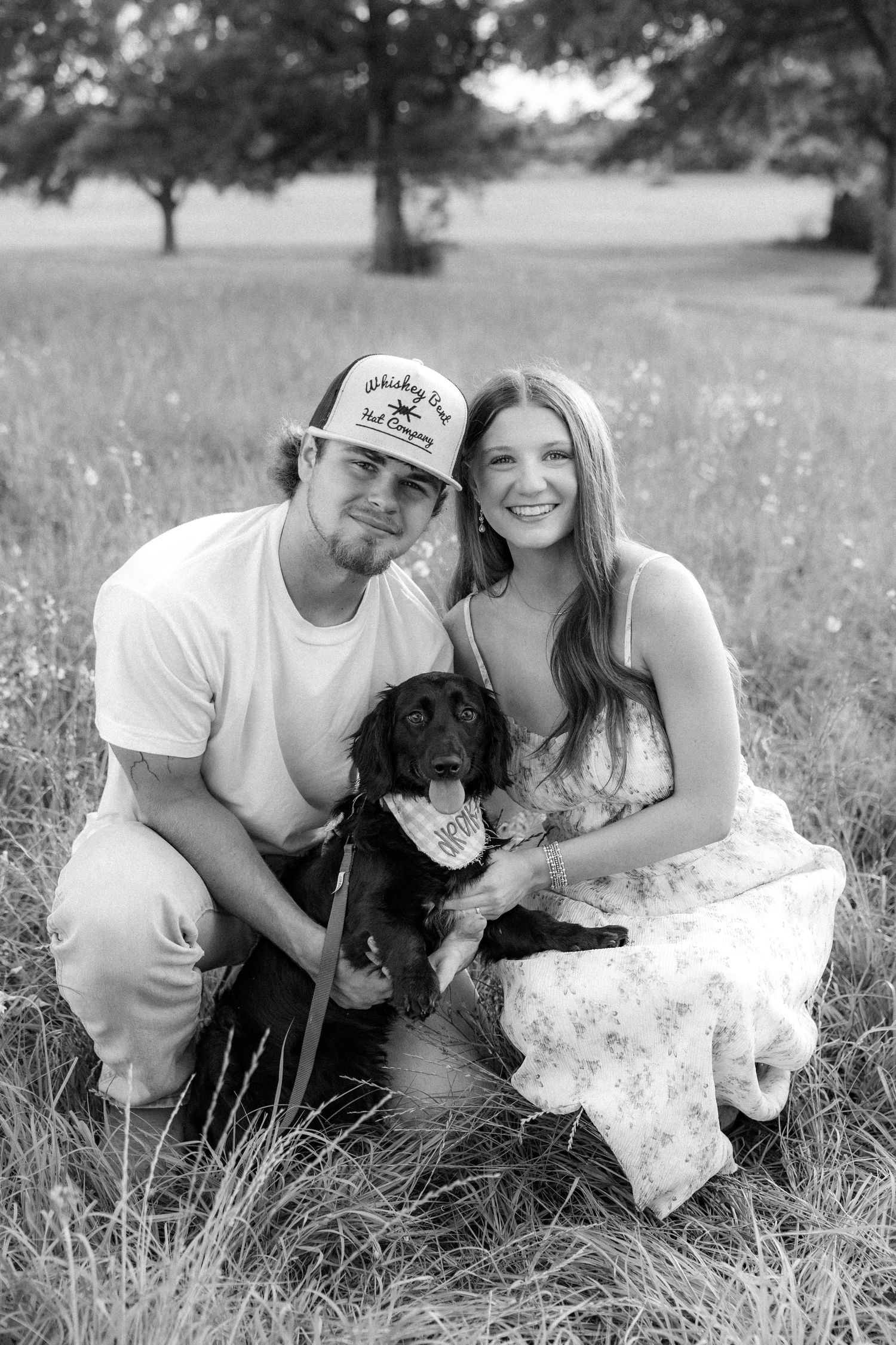 Romantic couple photos in a natural grass field setting with large trees at sunset.