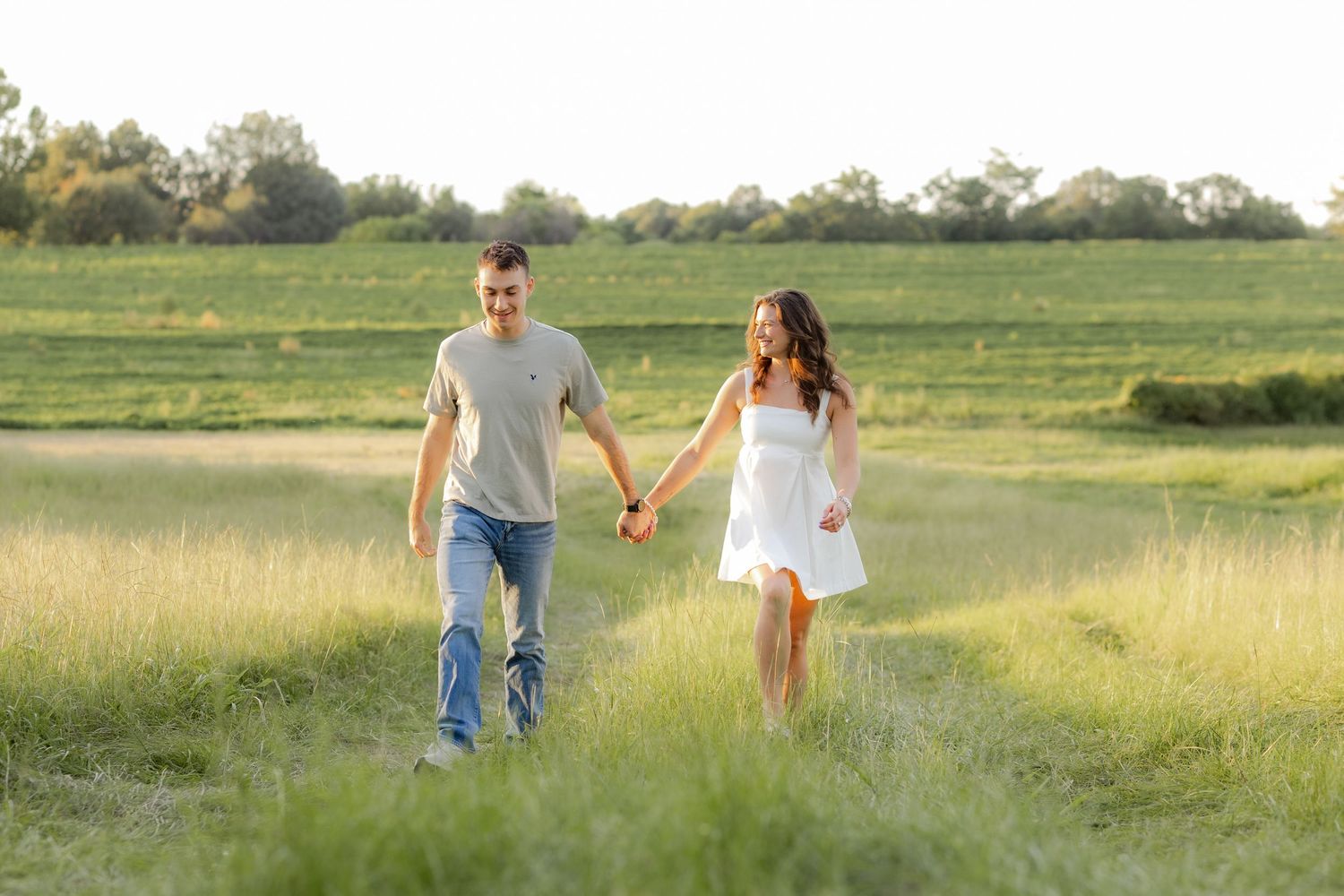 Couple walking in a grass field at sunset in Dothan, Alabama