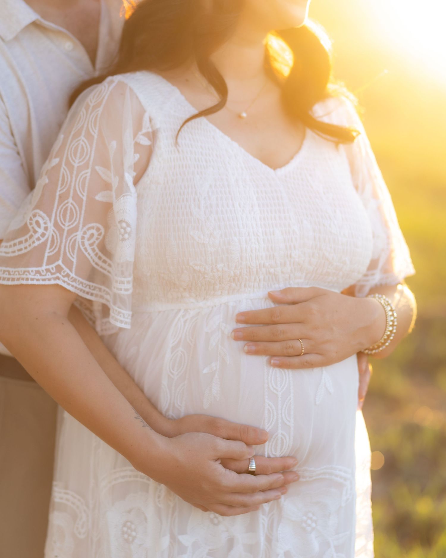Expecting couple holding each other in a grass field at sunset in Dothan, Alabama
