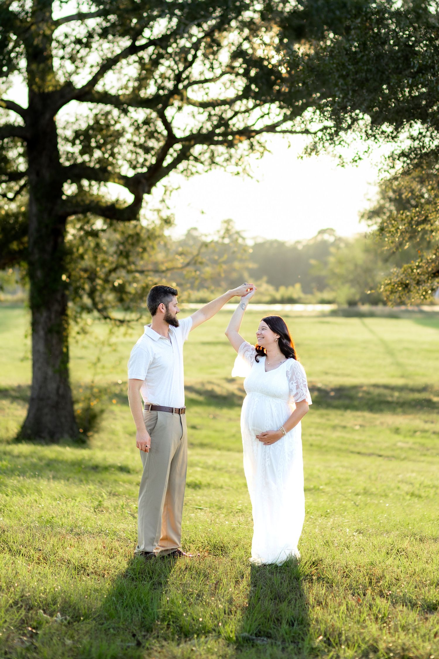 Expecting couple dancing in a grass field at sunset in Dothan, Alabama